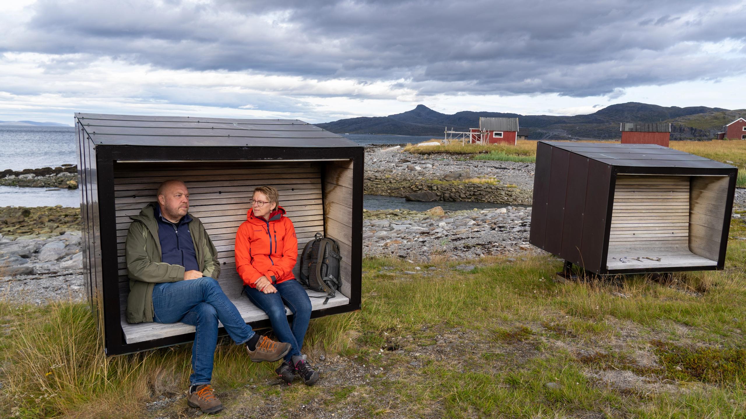 A man and a woman sit on a bench at Snefjord Rest Area