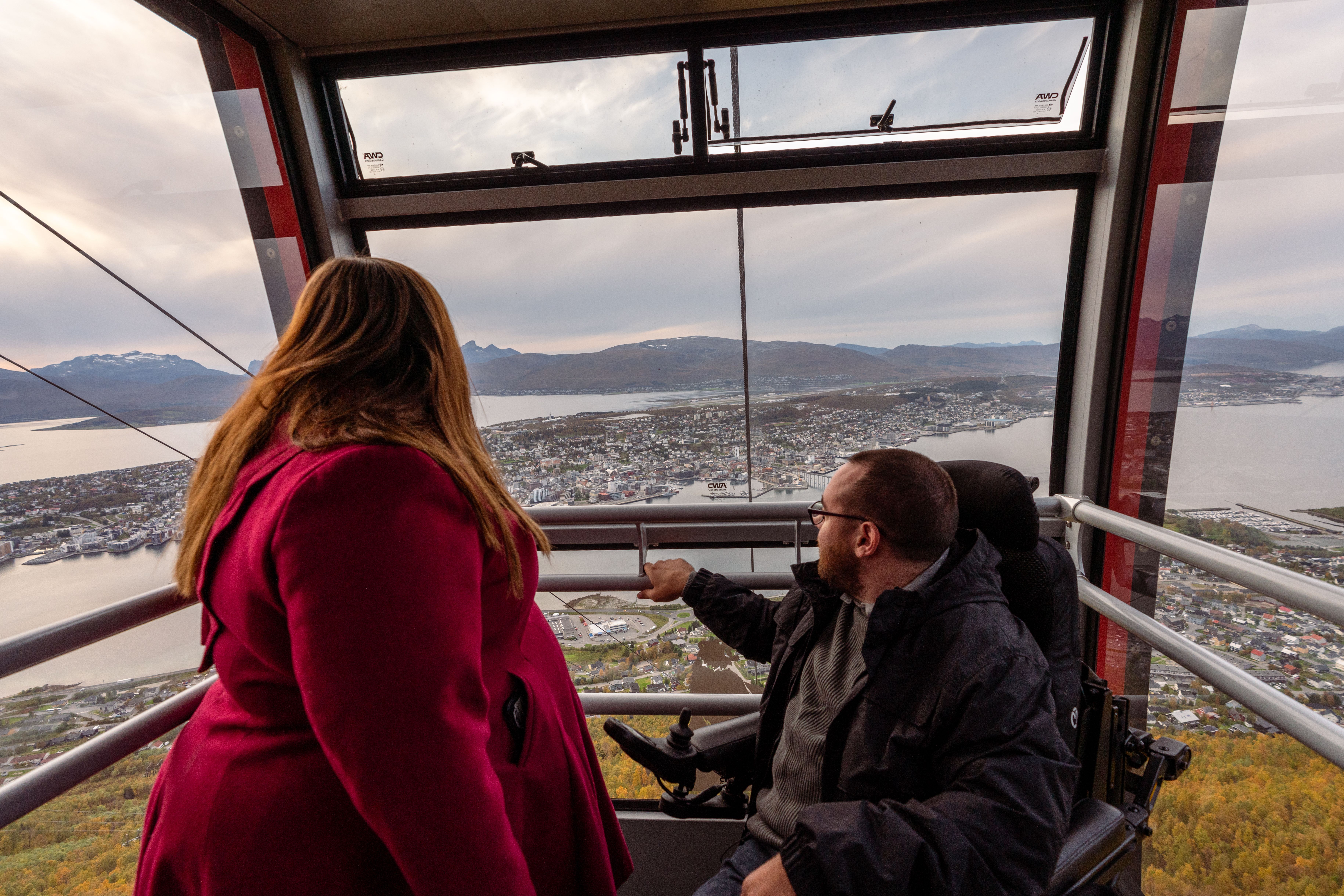 A woman and a handicapped man taking the cable car up to the mountain Storsteinen in Tromsø
