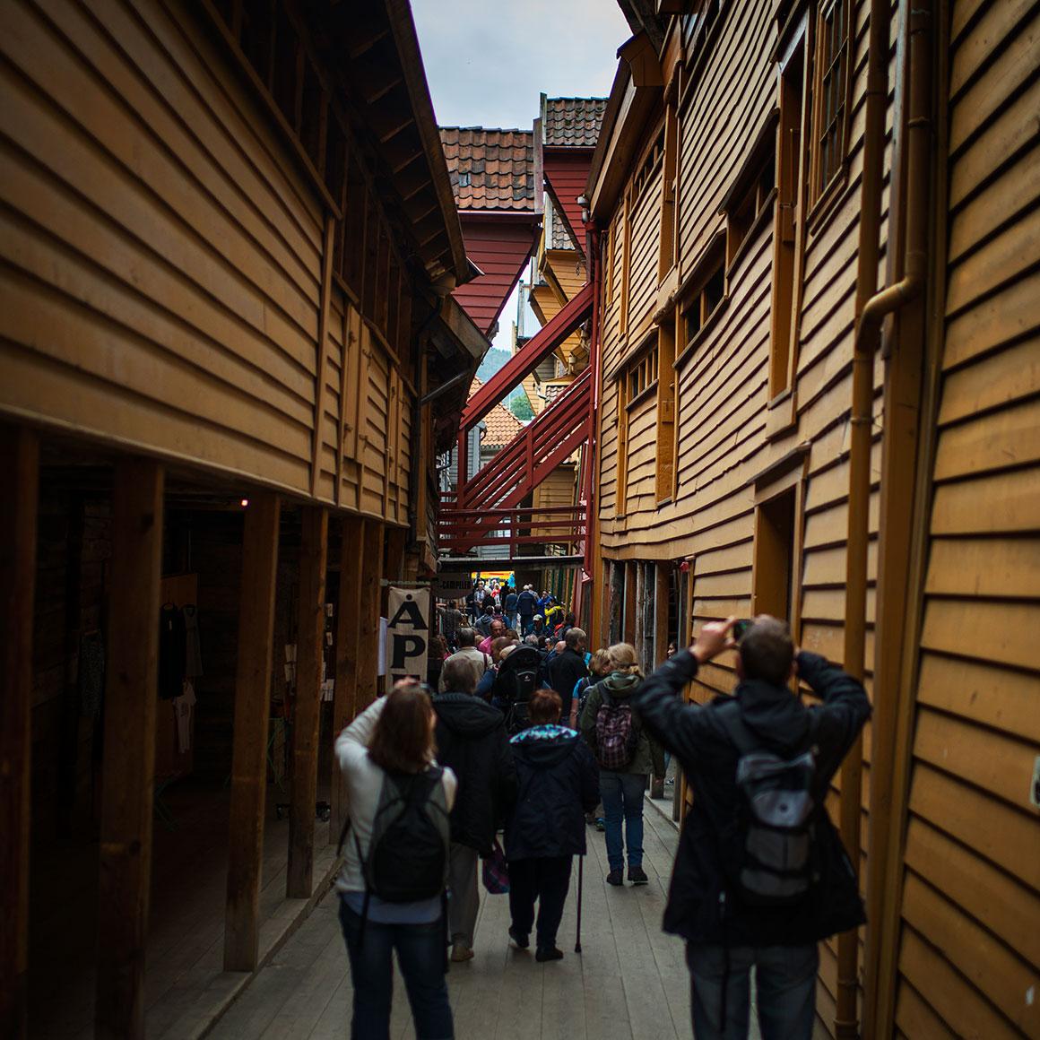 Folk fotograferer i et smug bak Bryggen i Bergen på Vestlandet