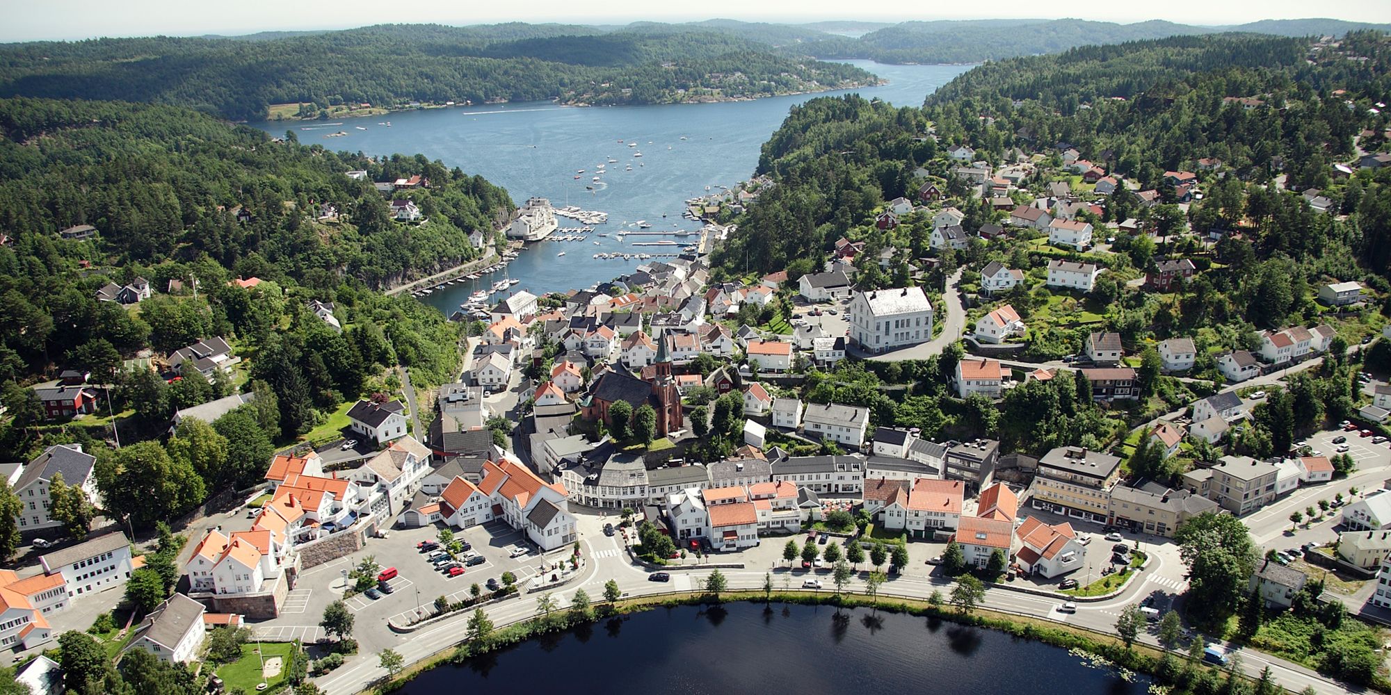 The idyllic white-painted city of Tvedestrand from the air, between the fjord and the city lake Tjenna. Southern Norway.