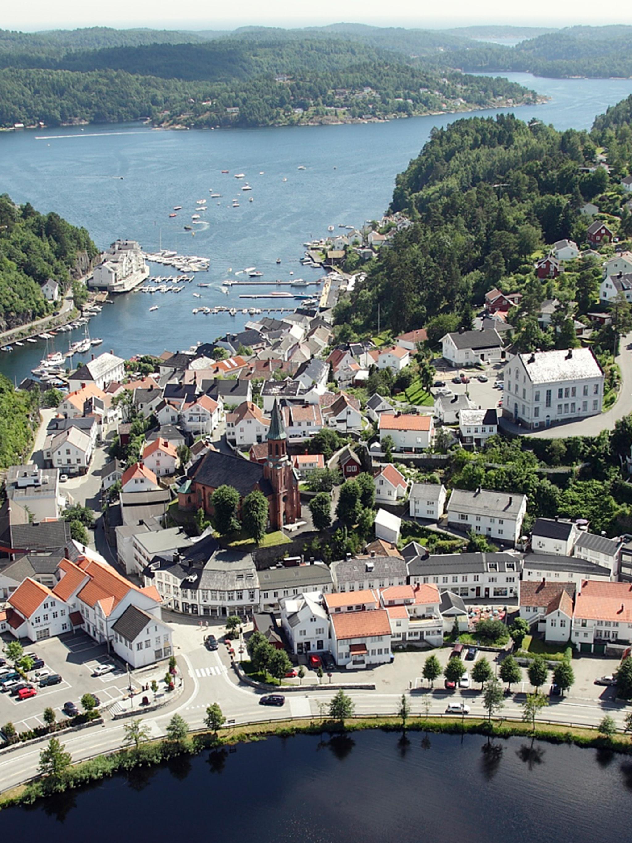 The idyllic white-painted city of Tvedestrand from the air, between the fjord and the city lake Tjenna. Southern Norway.