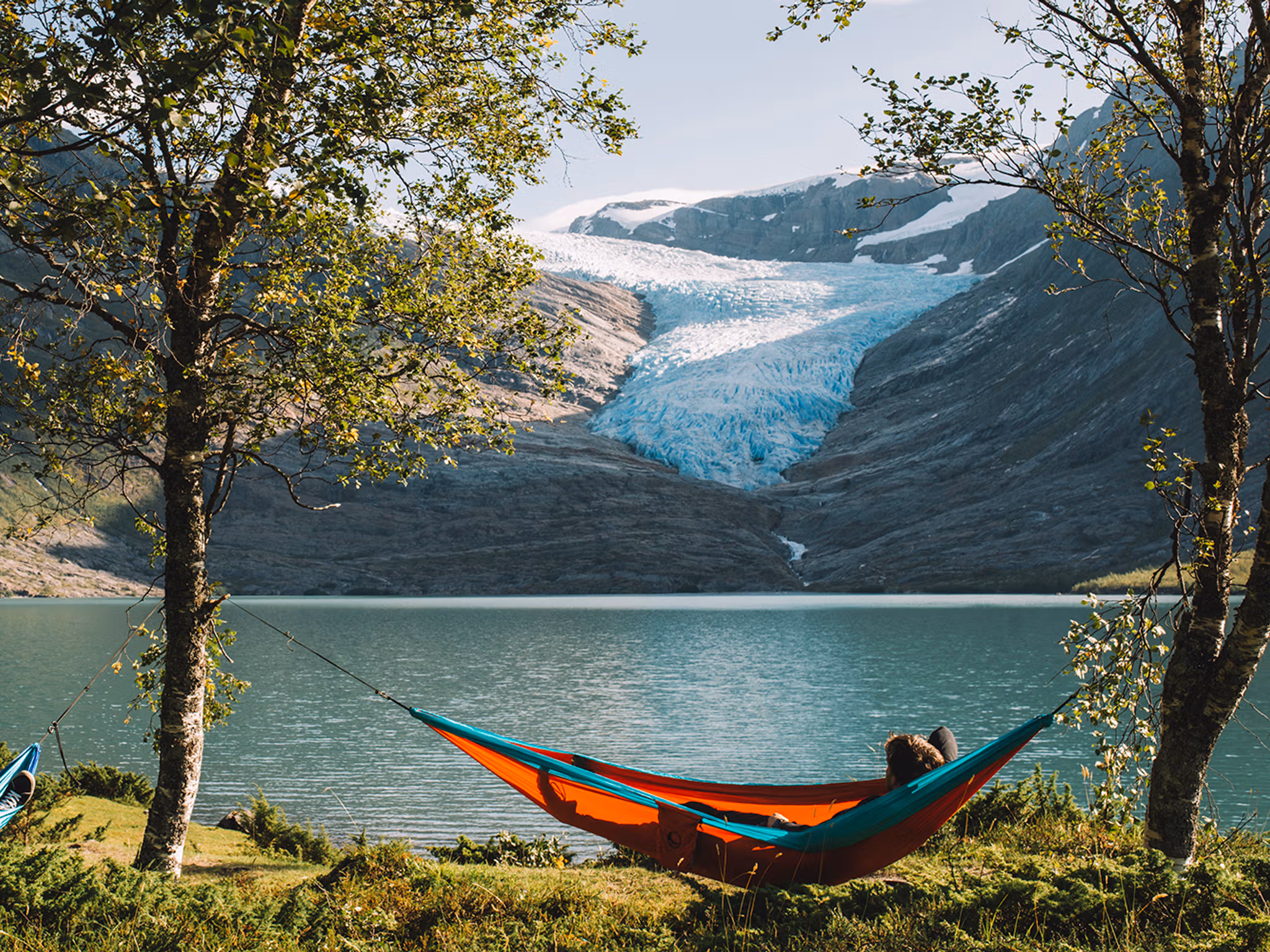 People in hammocks in front of the Svartisen glacier in Helgeland, Northern Norway