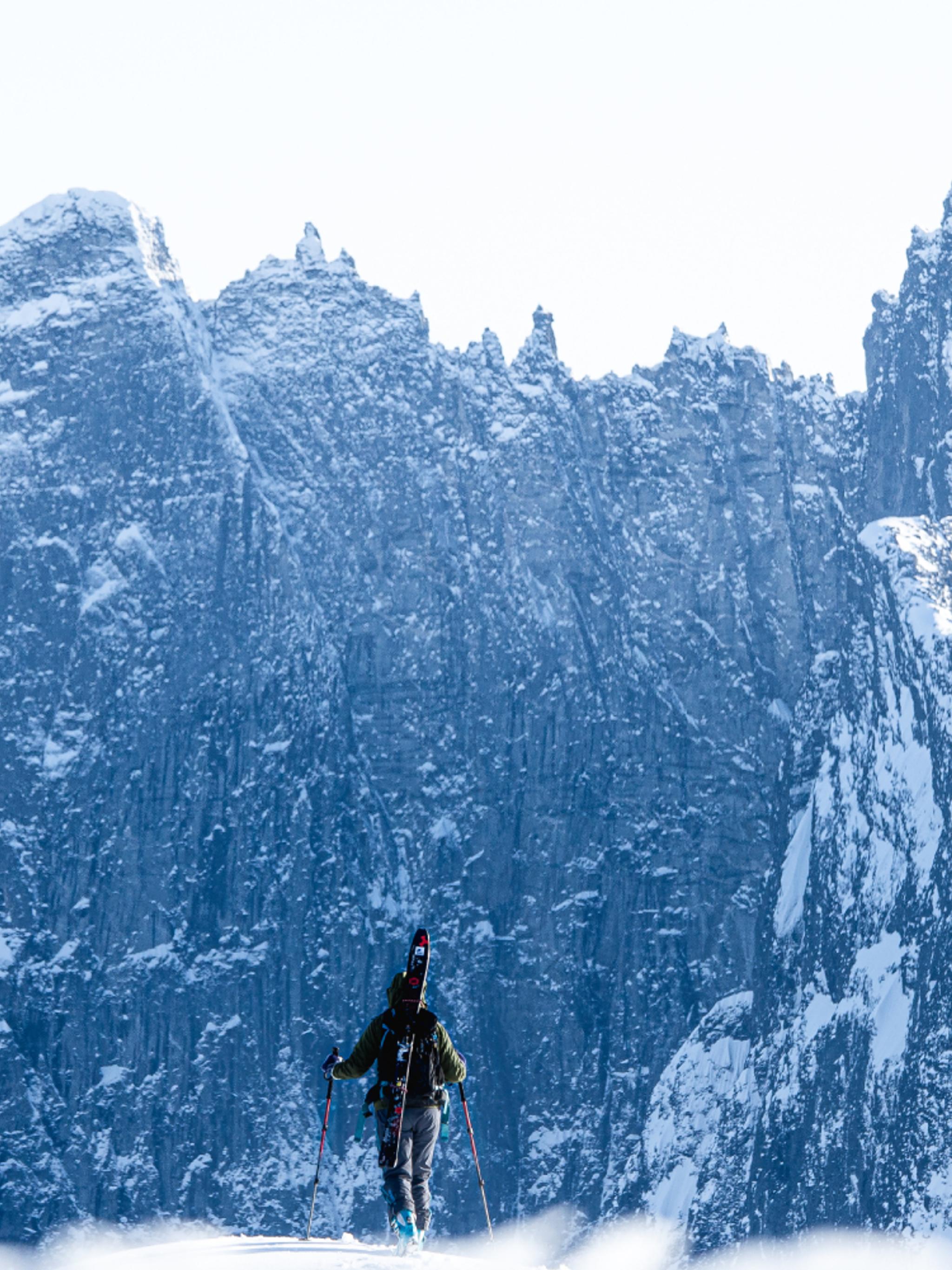 A person with skies looking at Trollveggen in Winter