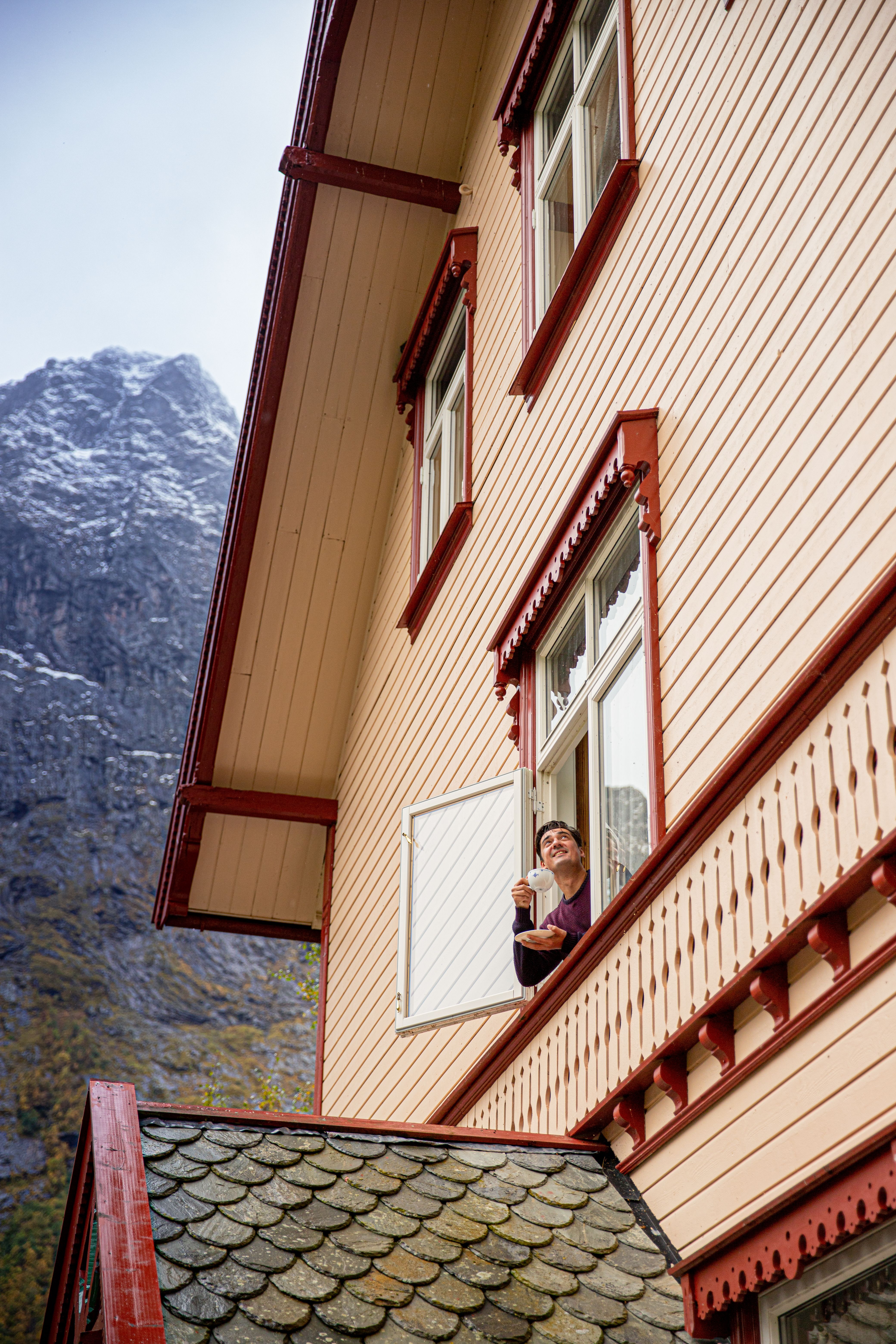 A man looks out of a window at Hoten Union Øye by the Hjørundfjord in Fjord Norway