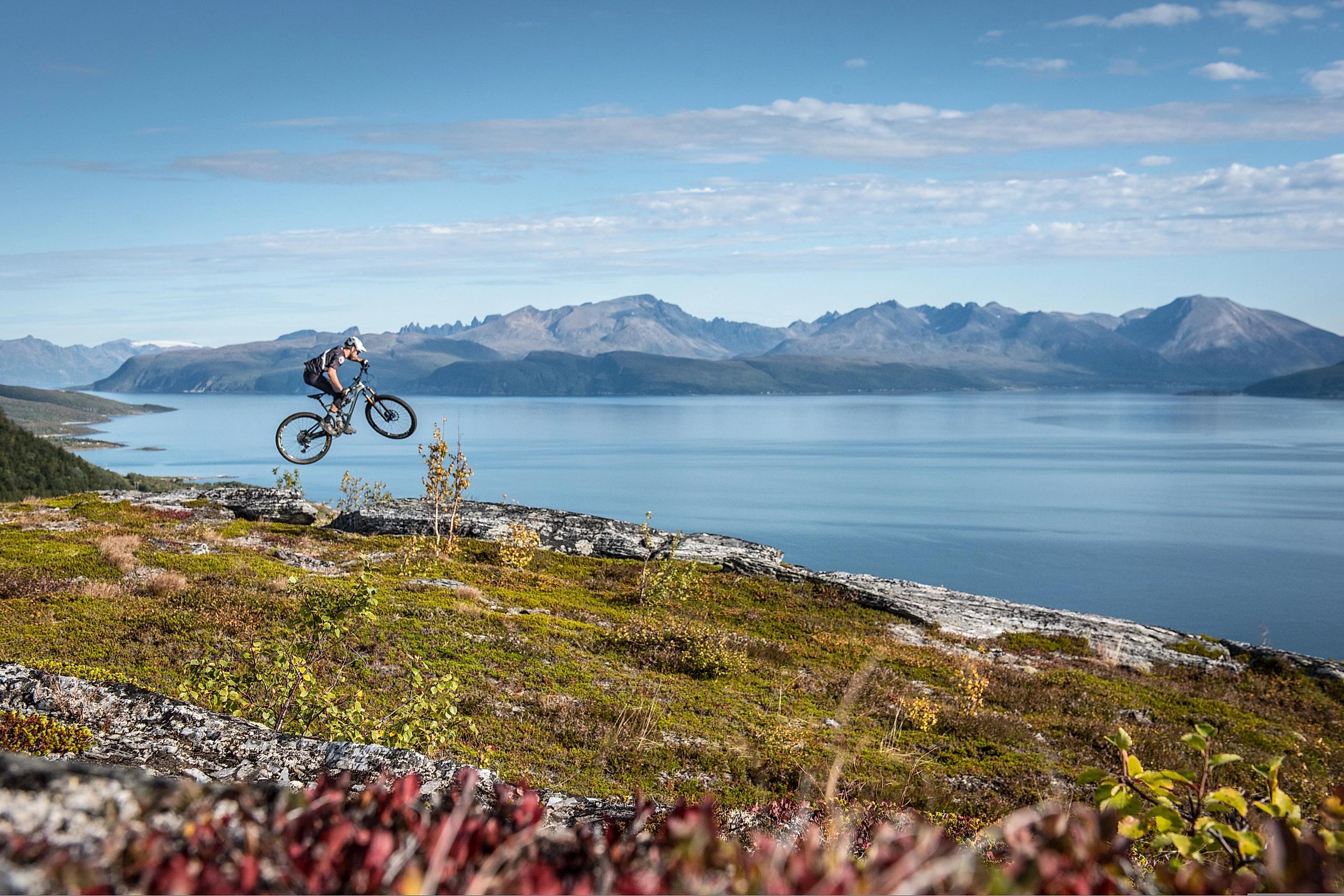 A person jumping with his mountain bike in the mountains in the Lyngenfjord region, Northern Norway