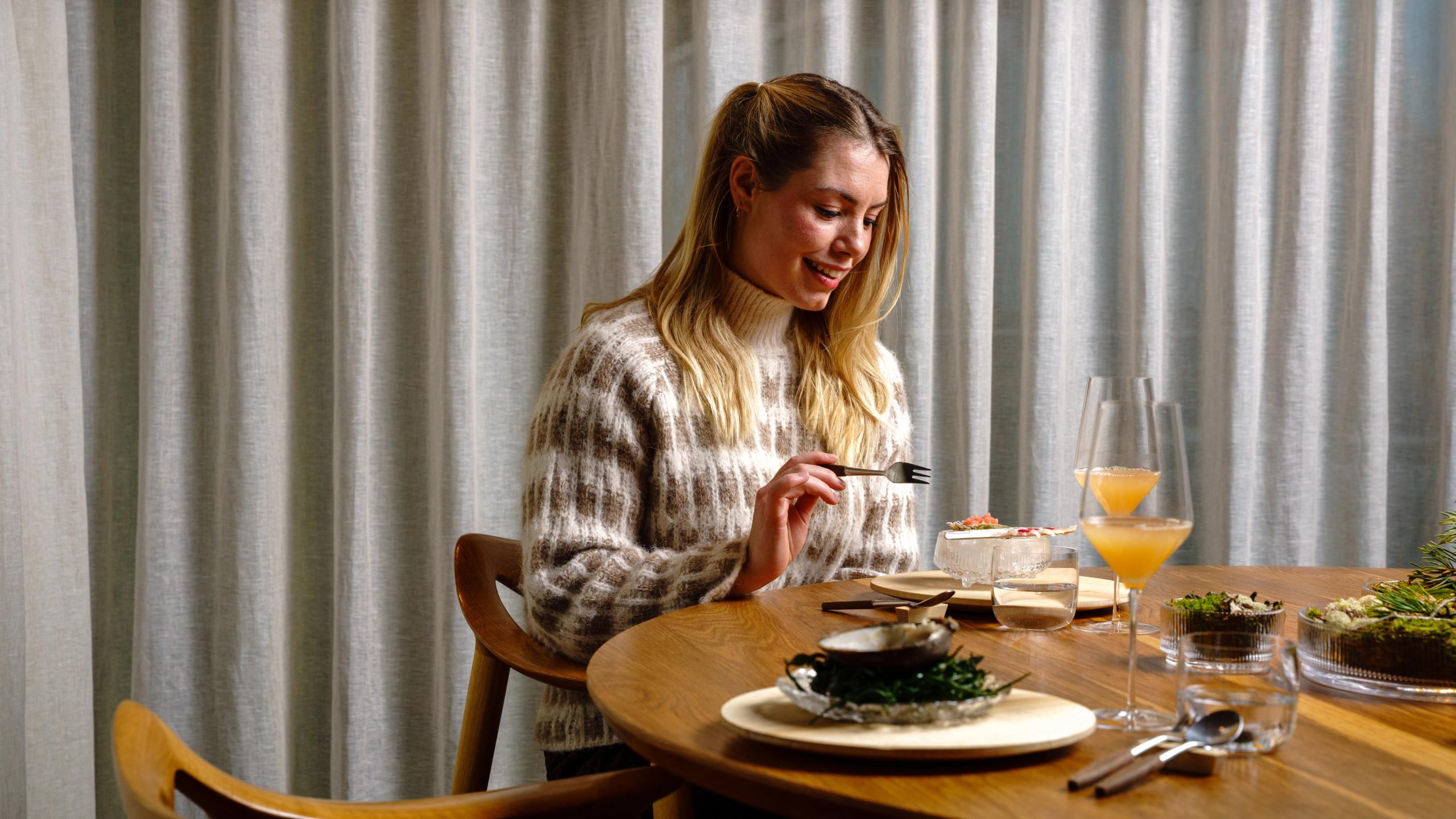 Dame som nyter gourmetmat på Credo på Nasjonalbiblioteket i Oslo.