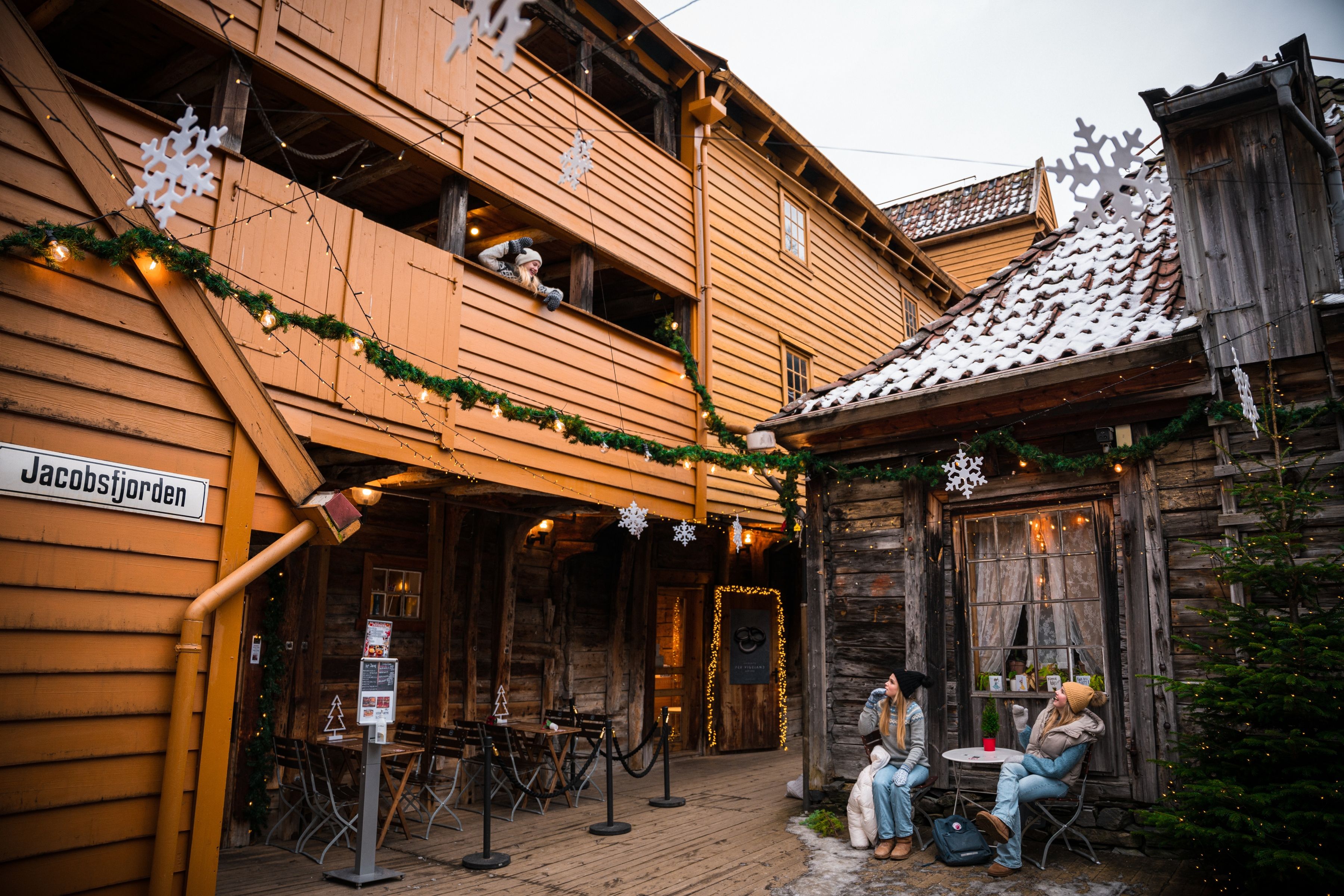 Three girls in the Christmas decorated passages of Bryggen wharf in Bergen, Fjord Norway
