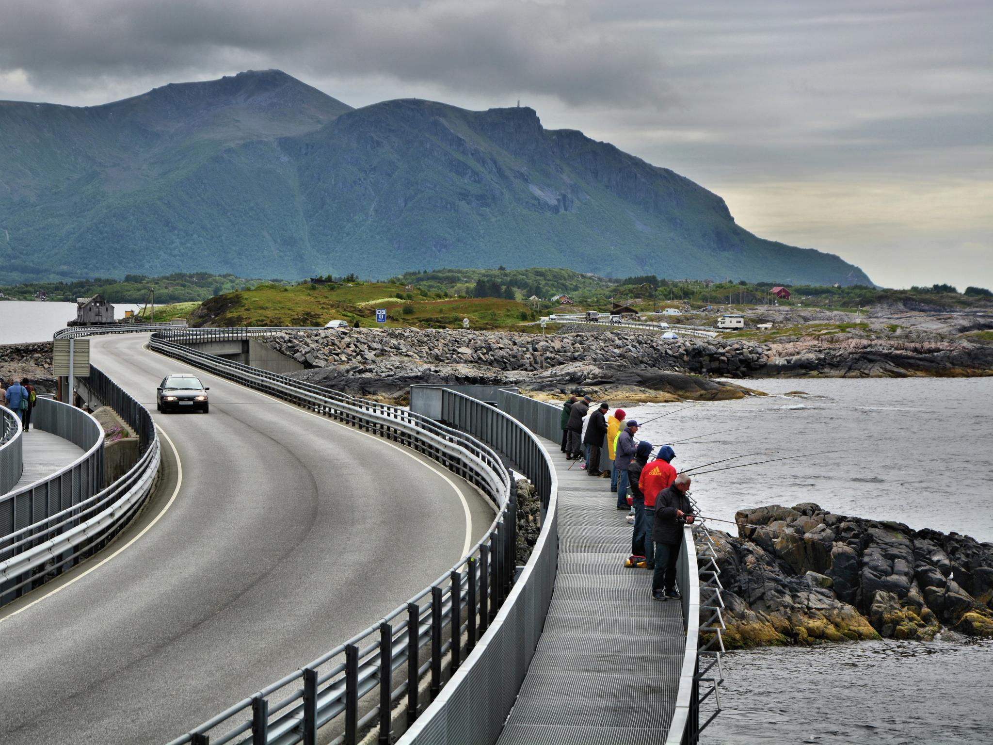 A group of people fishing from the Myrbærholmen fishing bridge on The Atlantic Road in Fjord Norway.