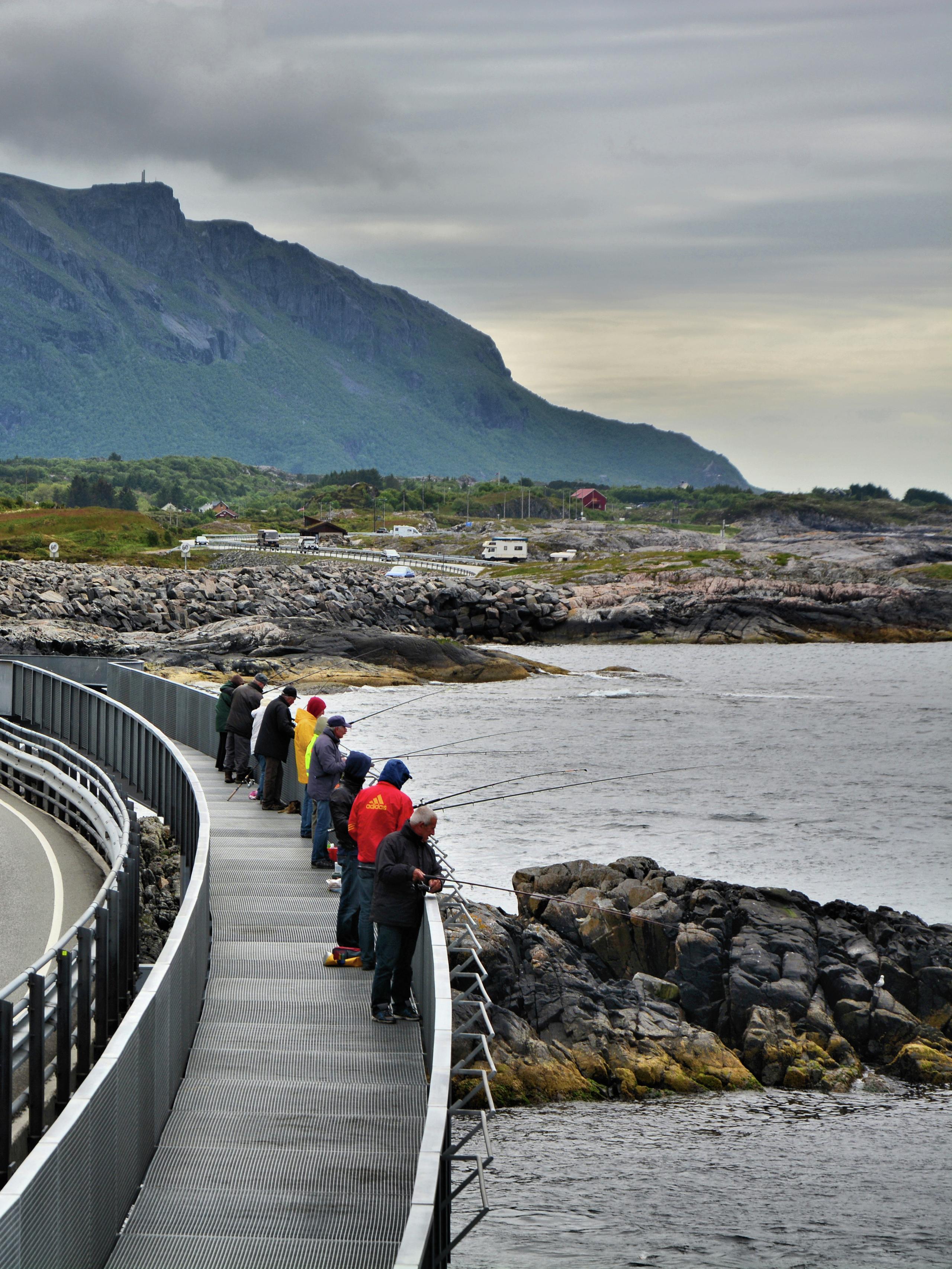A group of people fishing from the Myrbærholmen fishing bridge on The Atlantic Road in Fjord Norway.