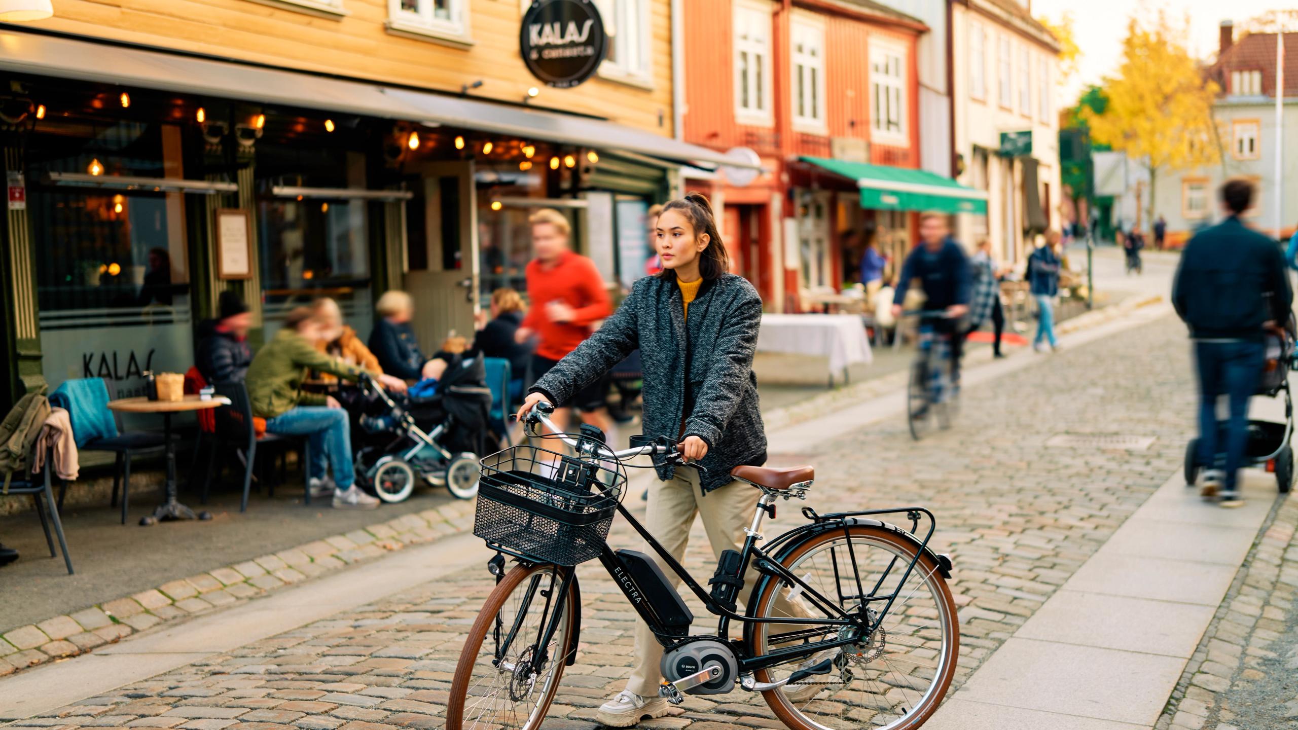 En kvinne triller sykkelen sin gjennom Bakklandet i Trondheim