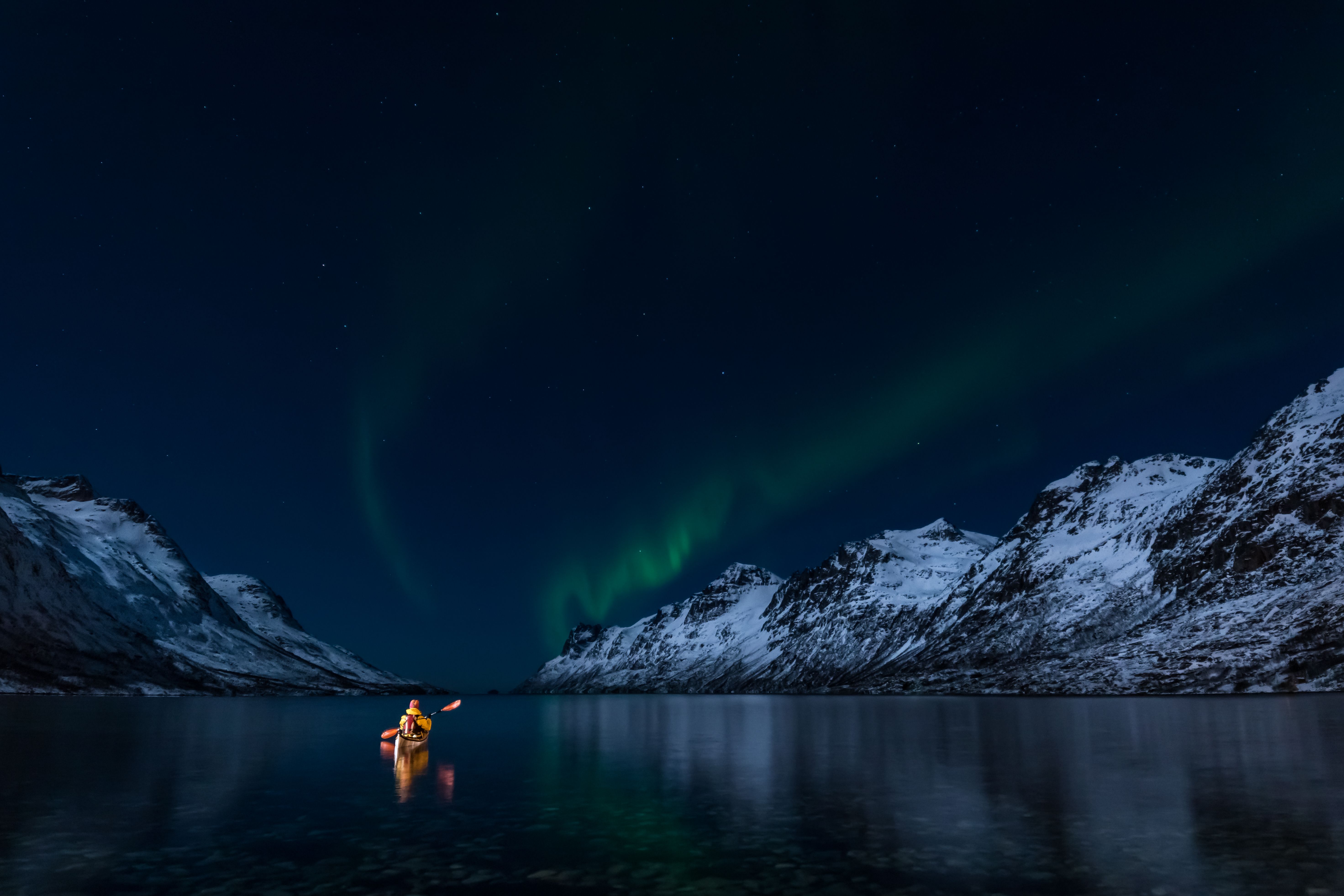 Kayakiste sous une aurore boréale dans les Lofoten, en Norvège du Nord
