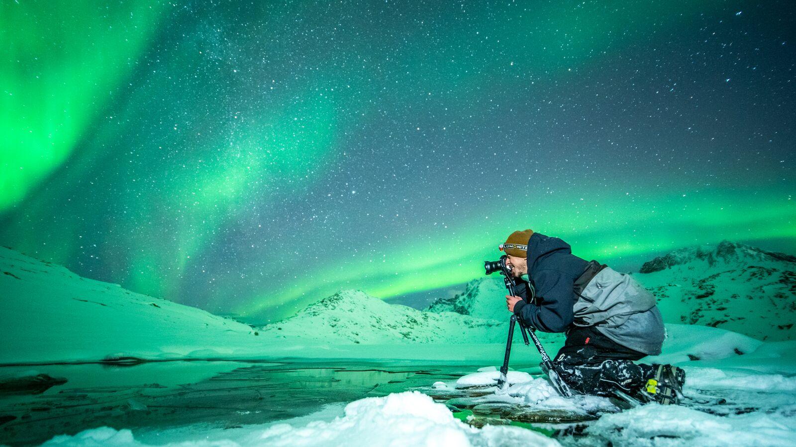 En mann tar bilde av nordlyset i Nord Norge