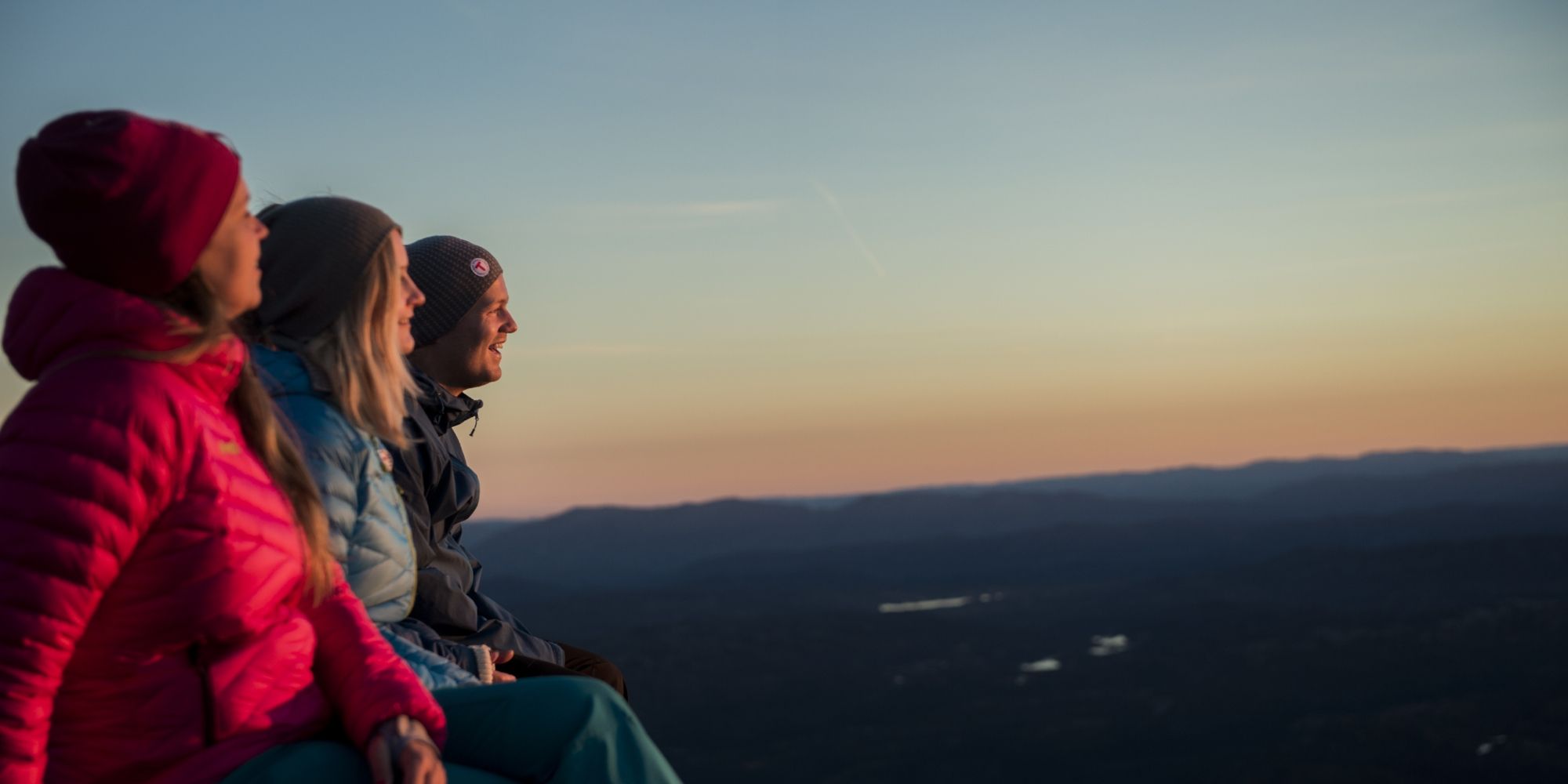 Three people enjoying the view from Mount Gaustatoppen in Telemark, Eastern Norway