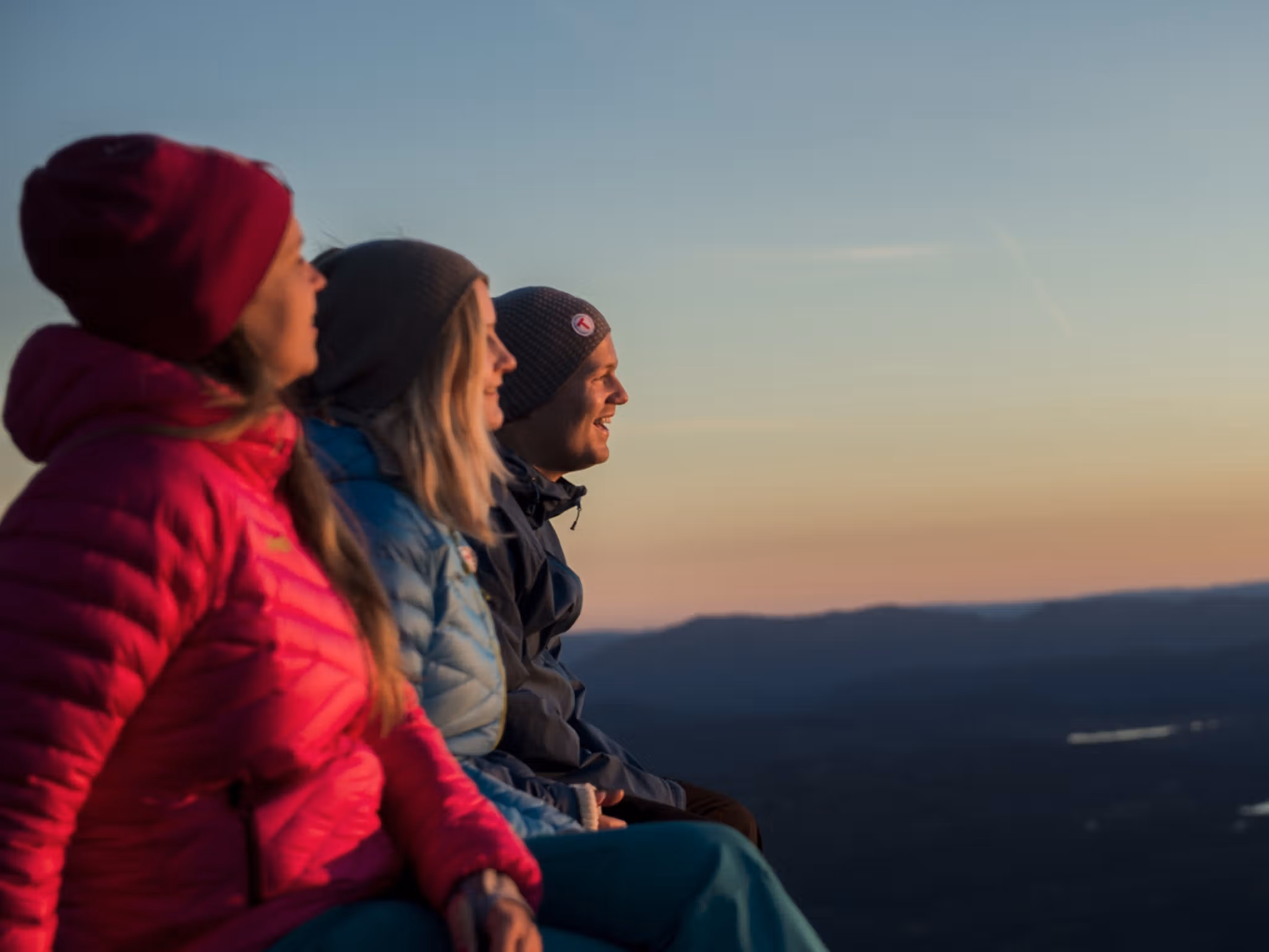 Three people enjoying the view from Mount Gaustatoppen in Telemark, Eastern Norway