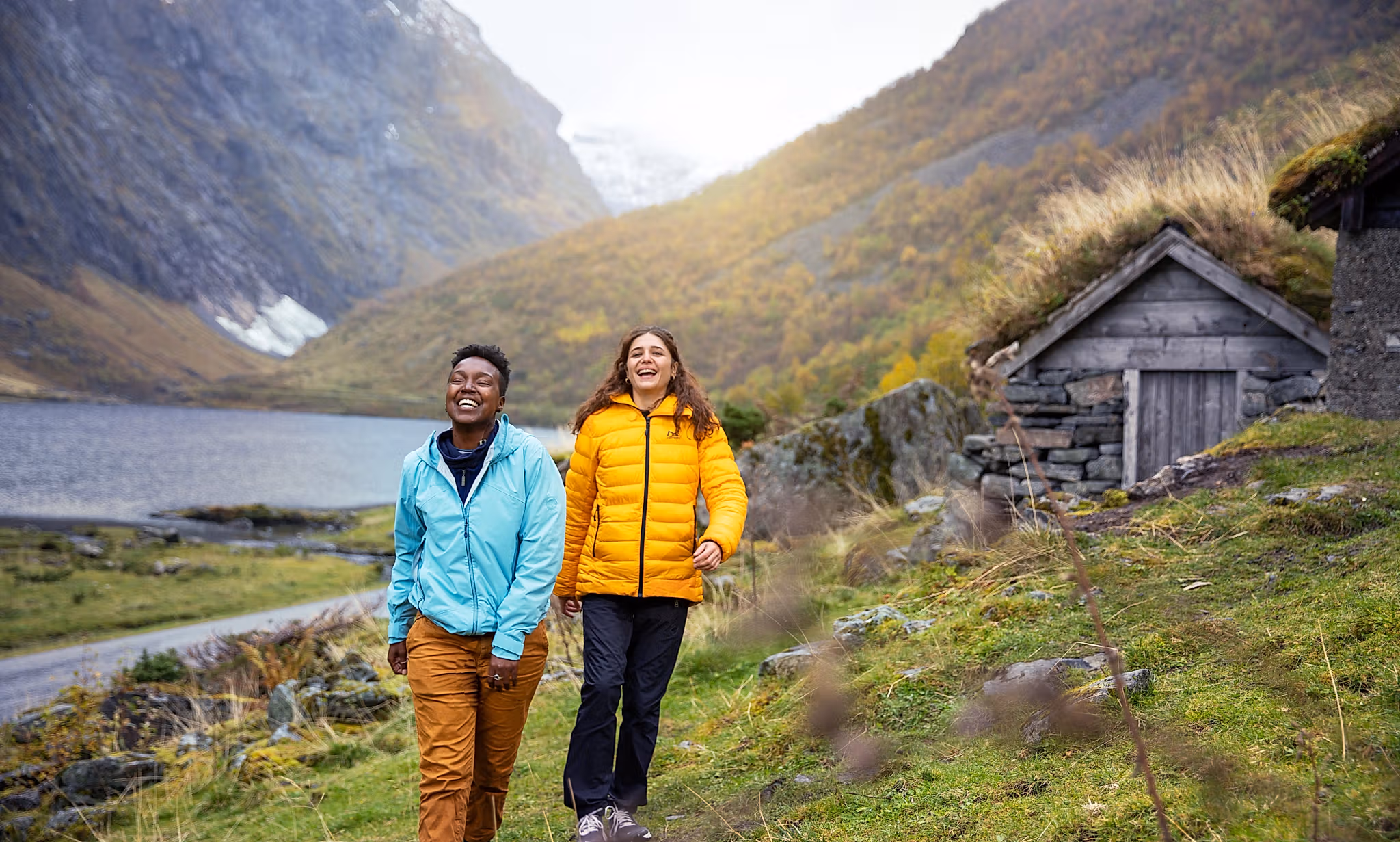 Two women hiking by the Hjørundfjord in Fjord Norway in autumn