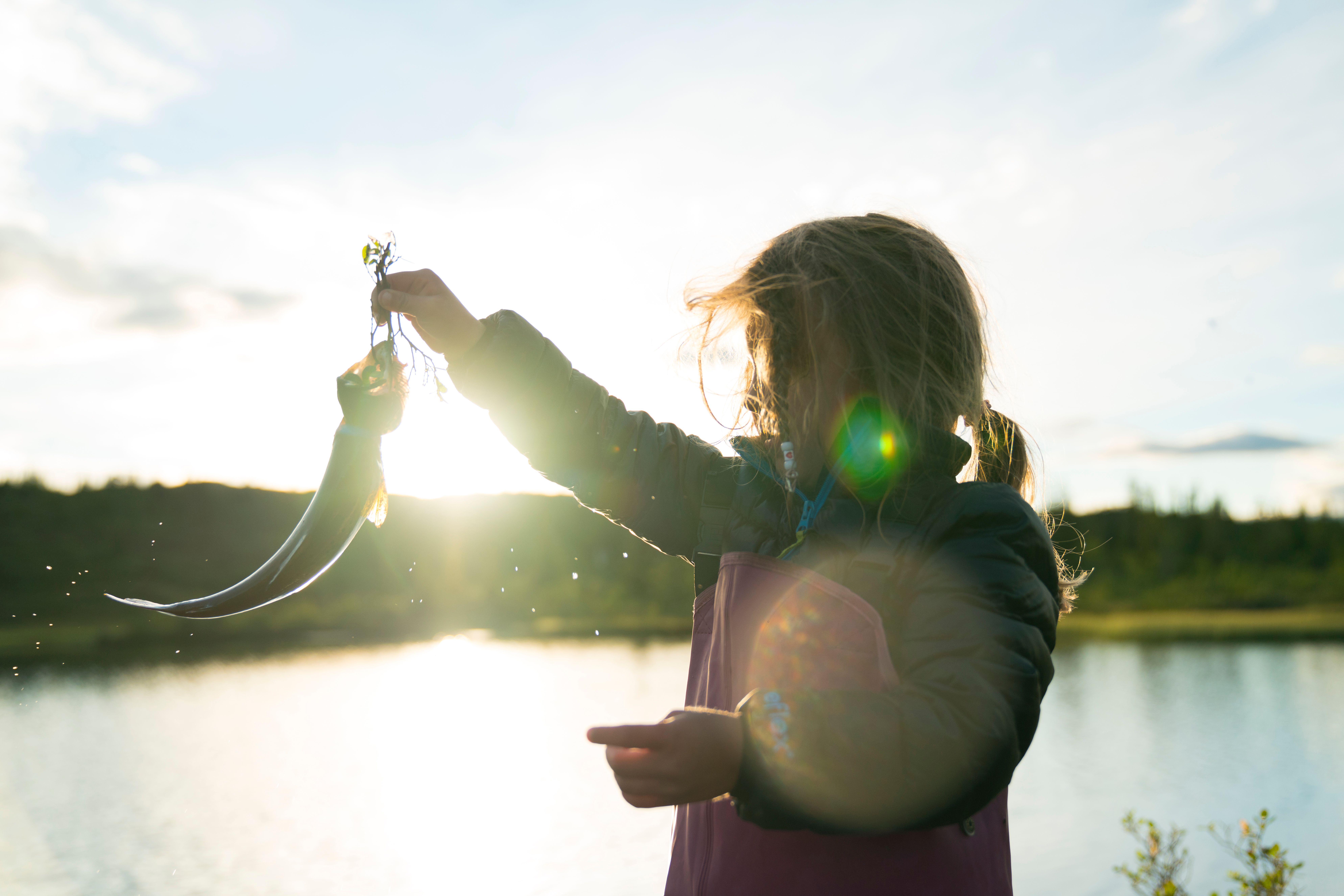 Liten jente holder opp fisk foran innlandsvann på Blefjell