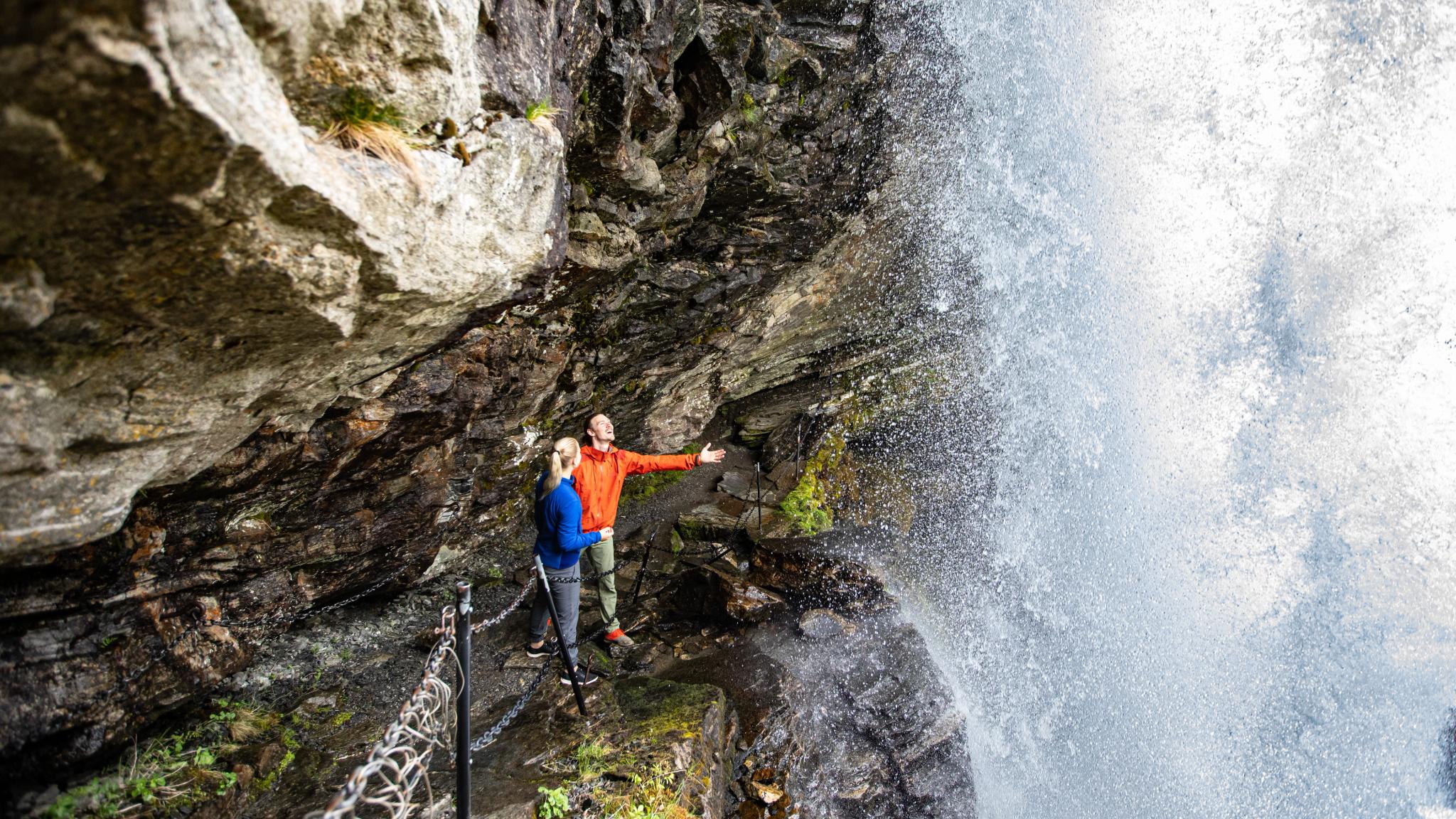 Couple hiking under the Fosseråsa in Geiranger, Fjord Norway