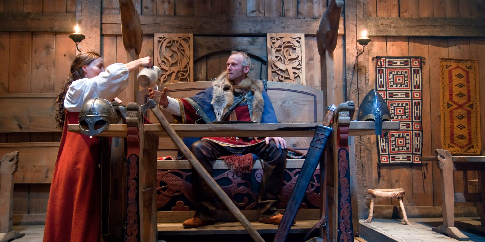 Viking throne with man and woman dressed as vikings in the Lofotr Viking Museum in Lofoten, Northern Norway