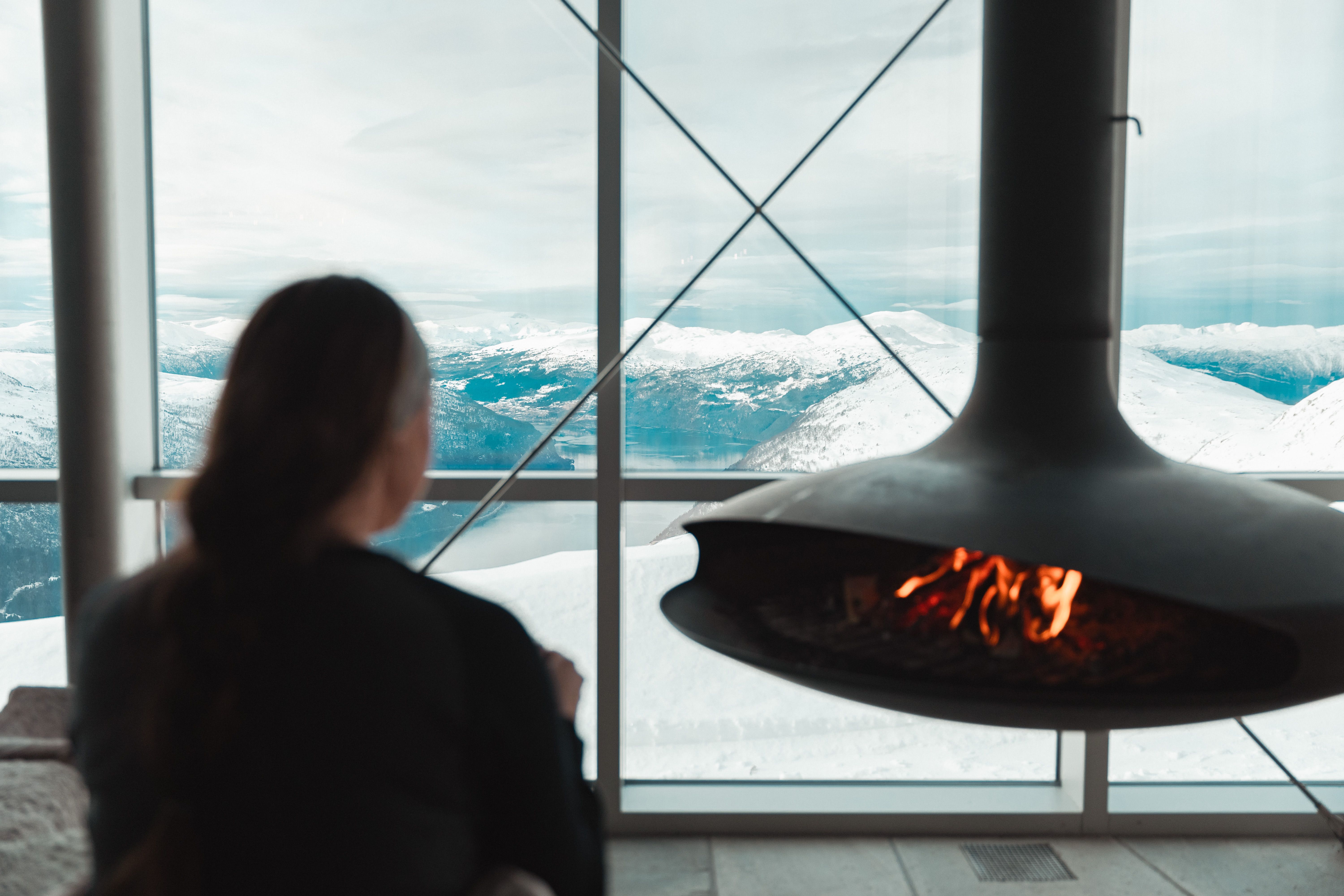 A woman by a fireplace with a hot chocolate.