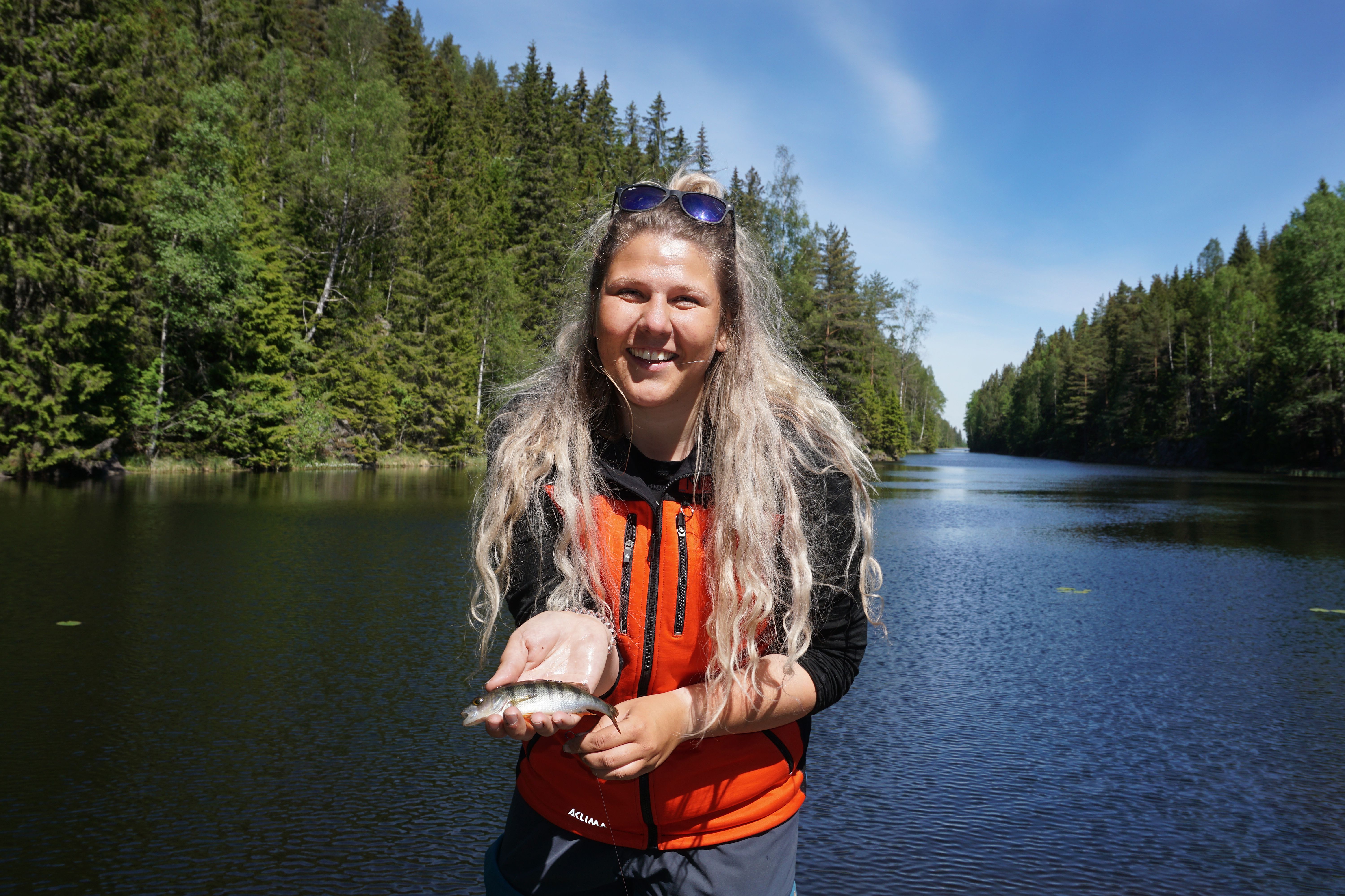 A woman holding a small fish in the fishing paradise Norway