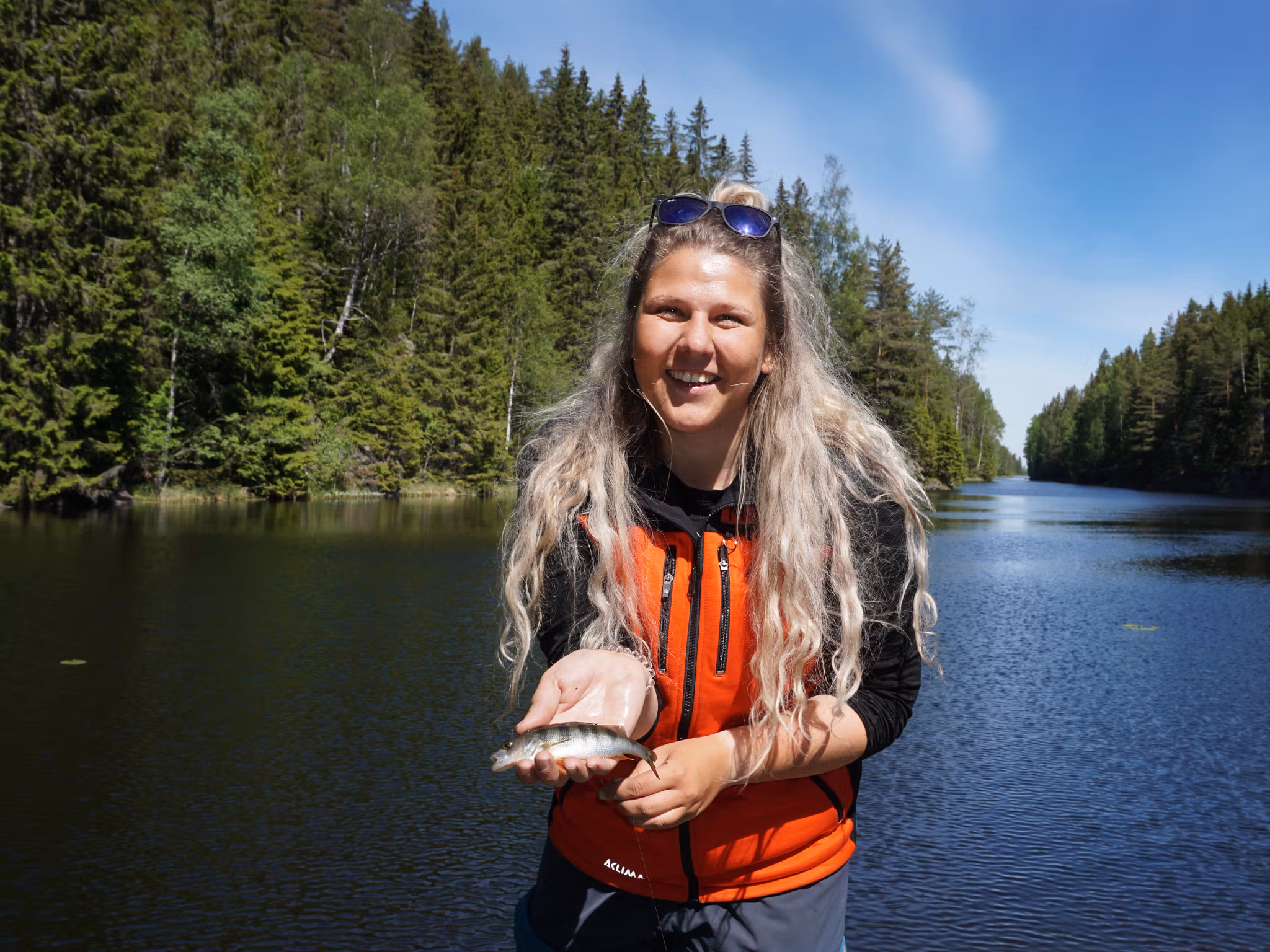 En kvinna håller en liten fisk i fiskeparadiset Norge