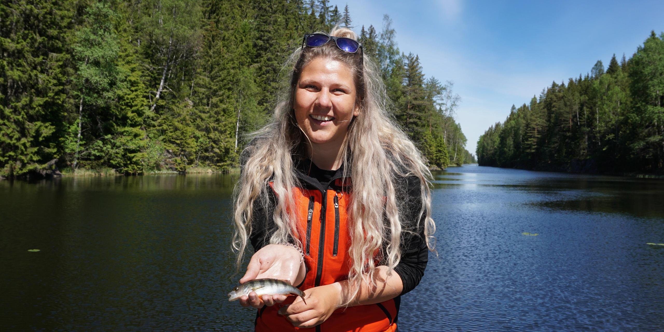 Eine Frau, die einen kleinen Fisch im Anglerparadies Norwegen hält.