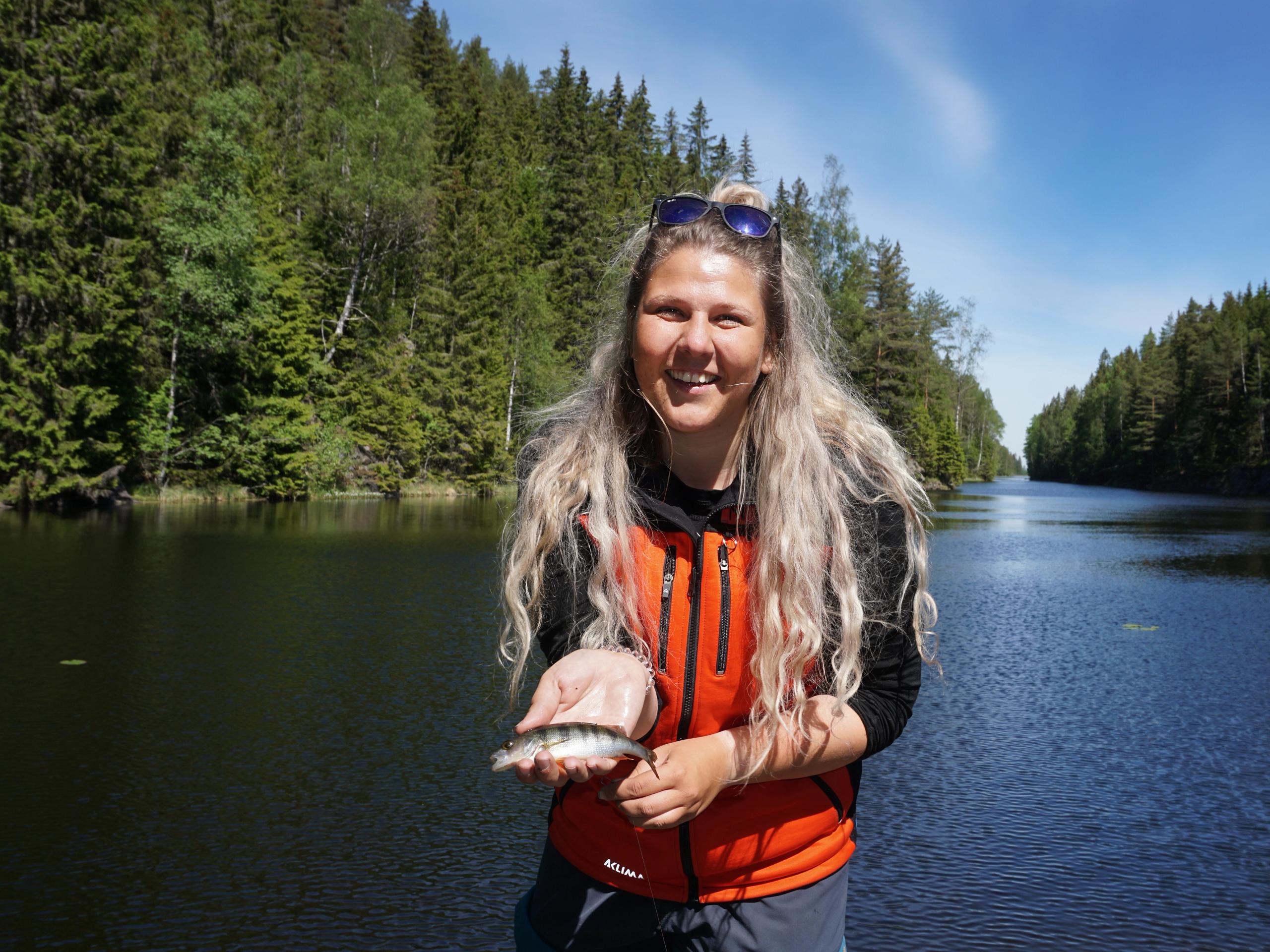 Eine Frau, die einen kleinen Fisch im Anglerparadies Norwegen hält.