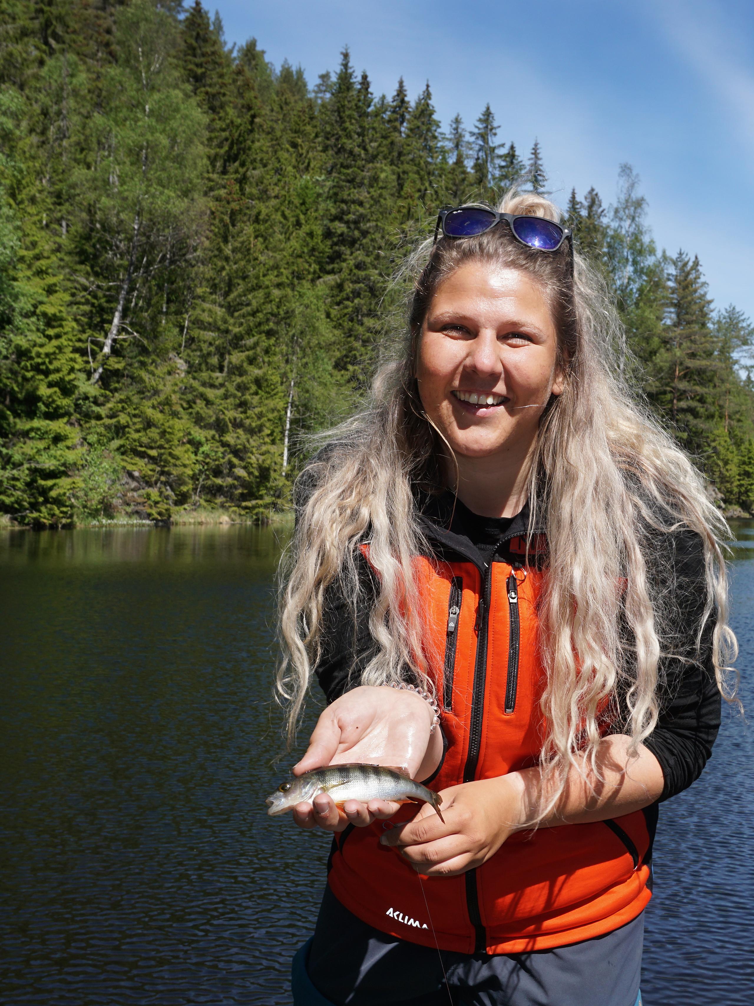 A woman holding a small fish in the fishing paradise Norway
