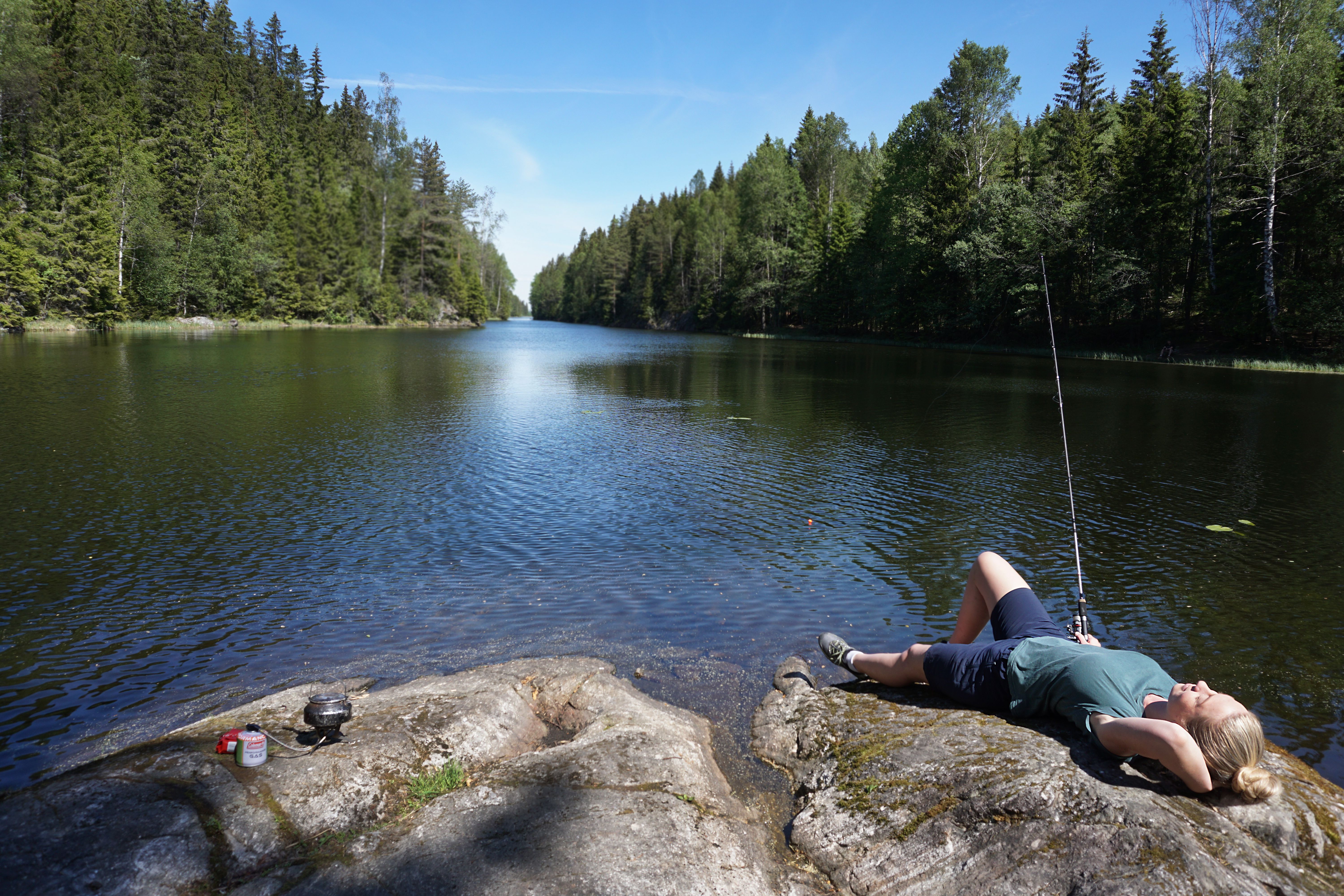 A woman lying down while fishing in a lake in Akershus, Eastern Norway