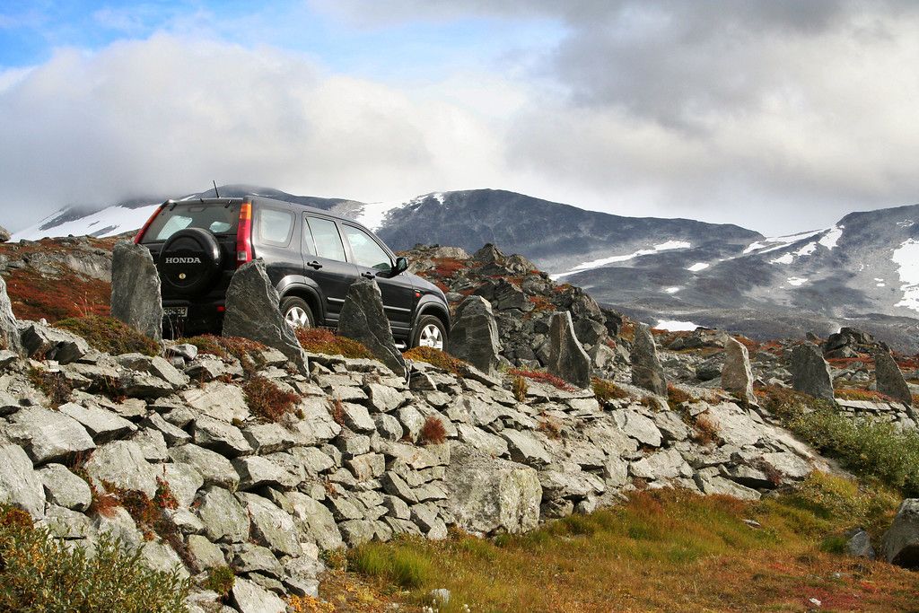A car driving on a road with a stone wall.