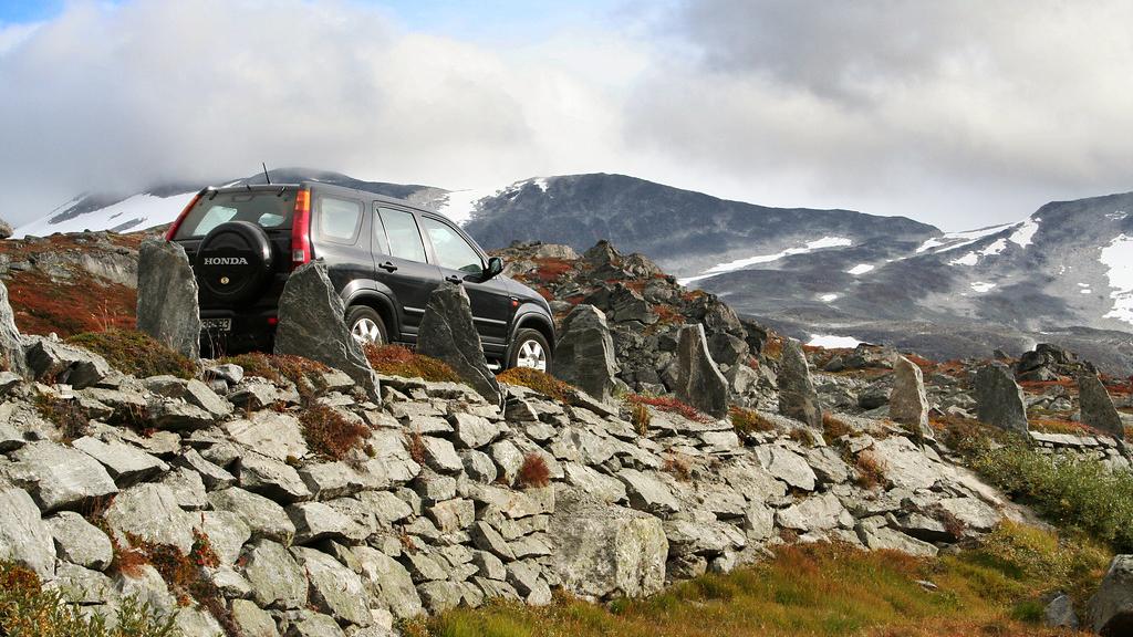 A car driving on a road with a stone wall.