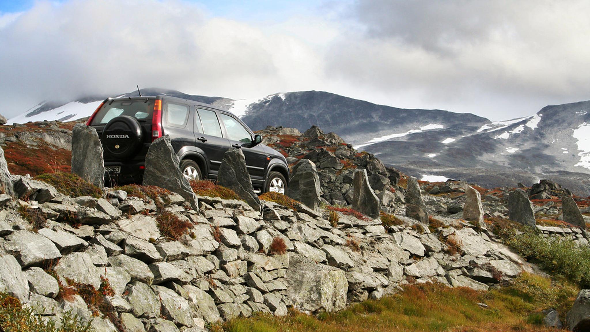 A car driving on a road with a stone wall.
