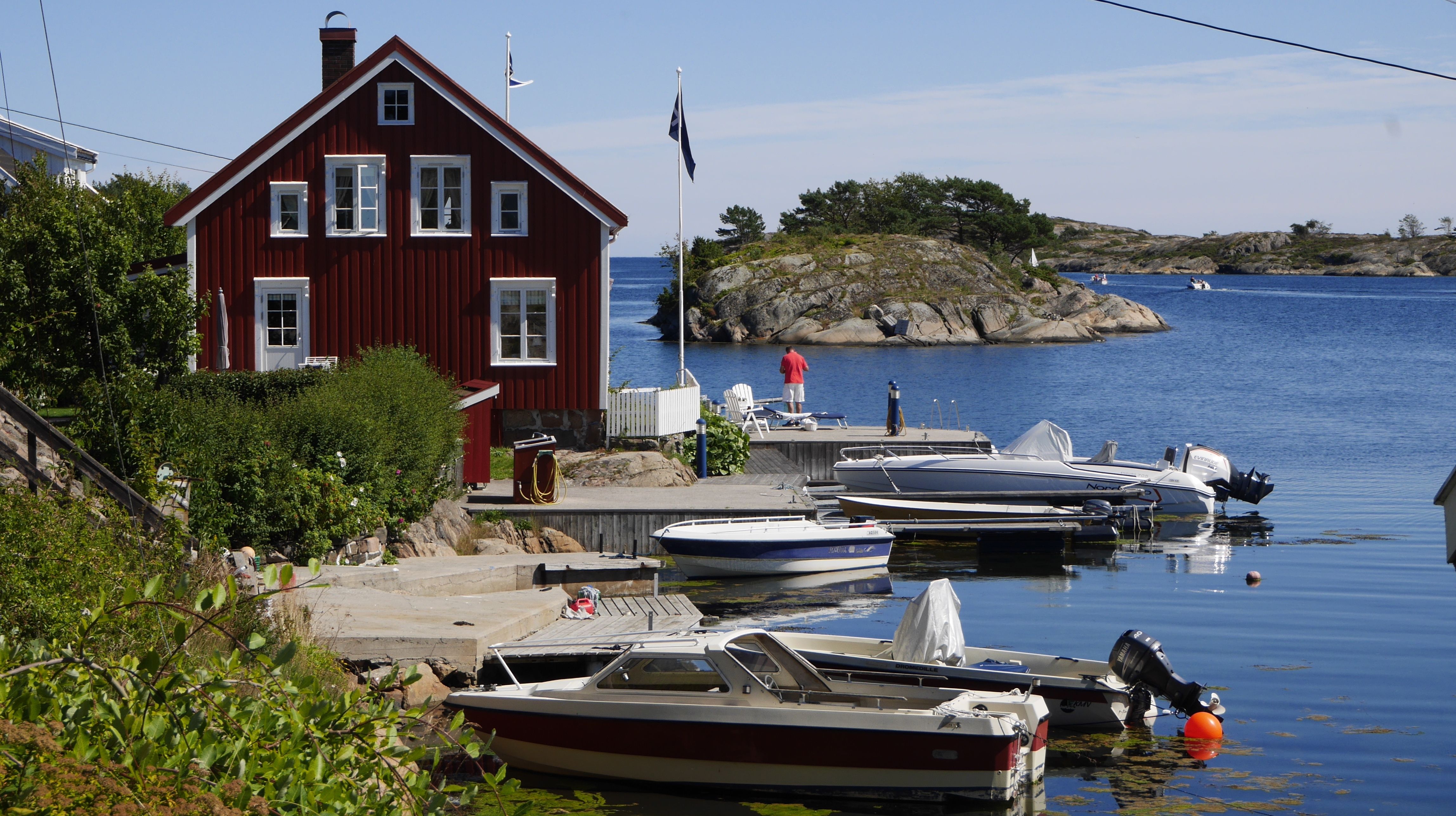 View of a house near the water and a few boats in Sandøya outside of Tvedestrand, Southern Norway