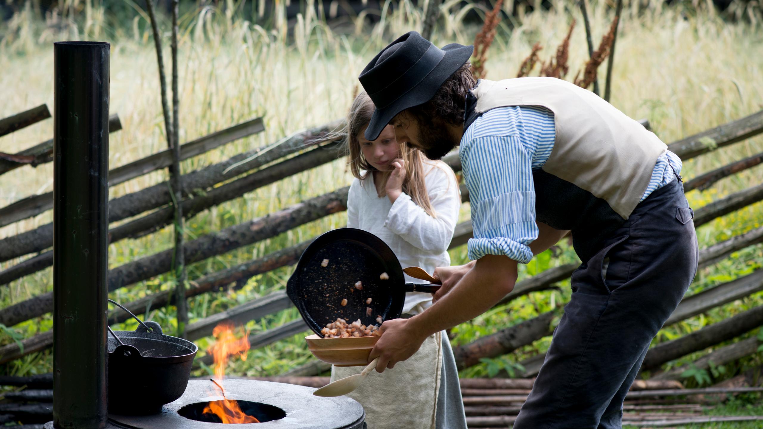 Father and daughter cooking outside