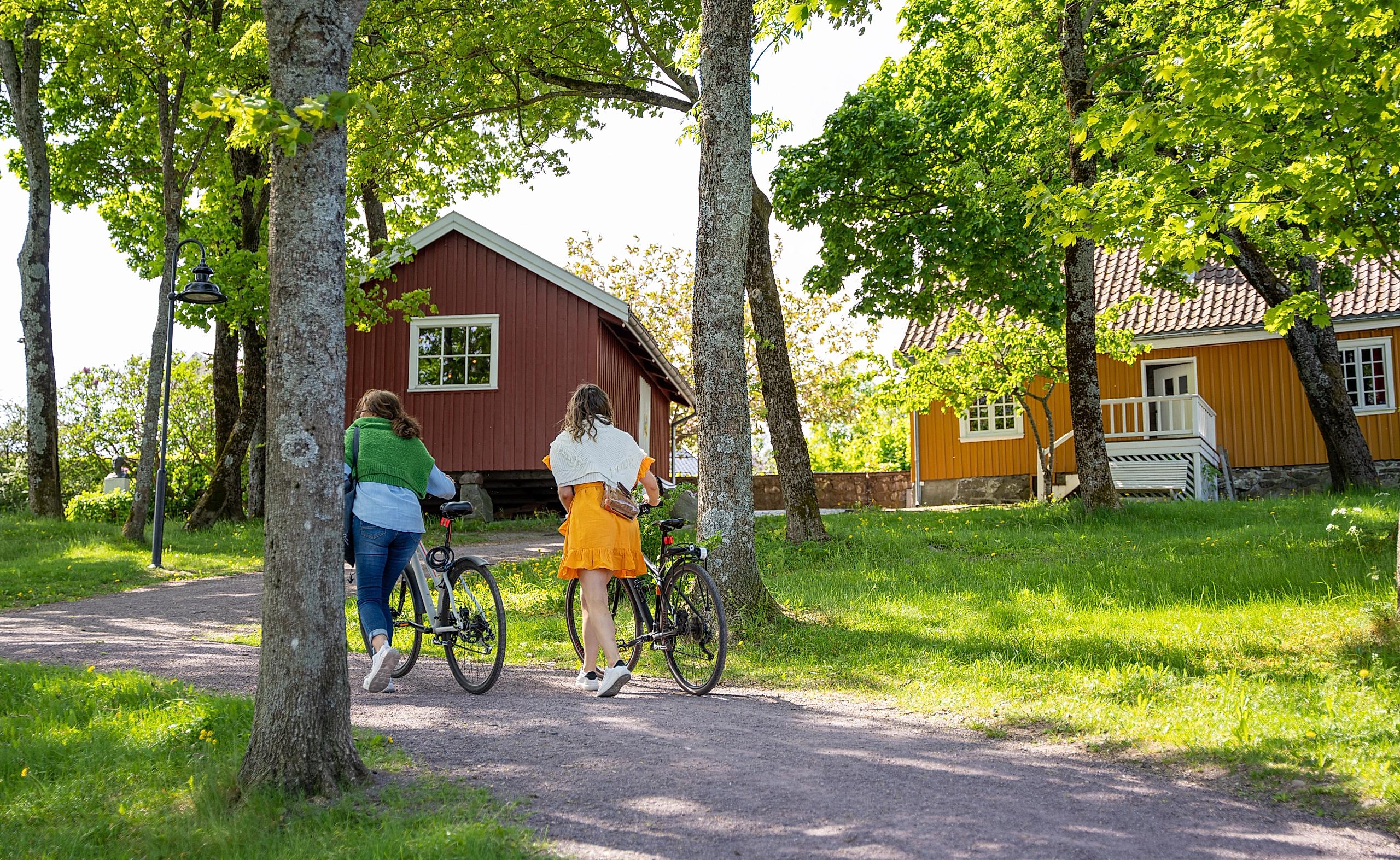 Two women walking with bike in front of Edvard Munch's old house in Åsgårdstrand