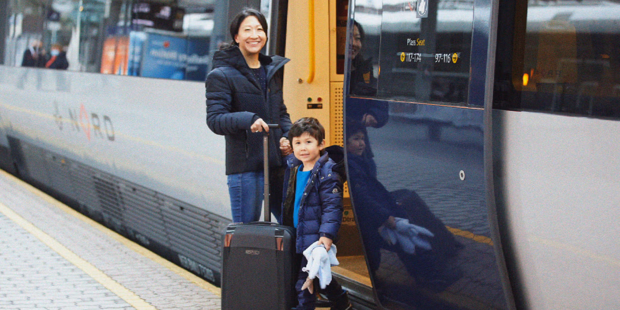 A women and a child is standing outside of a train.