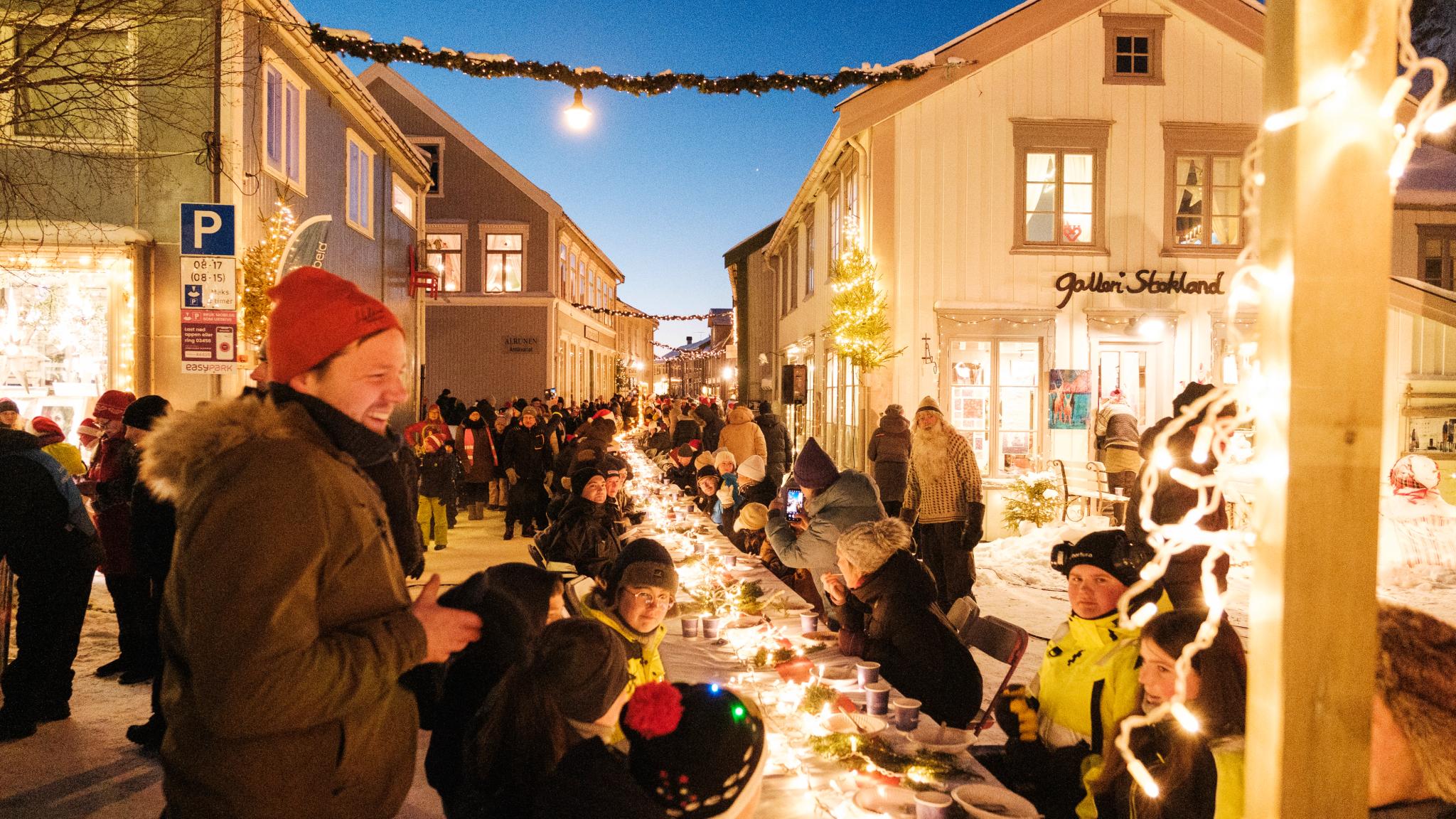 People enjoying porrige with a long table outside.