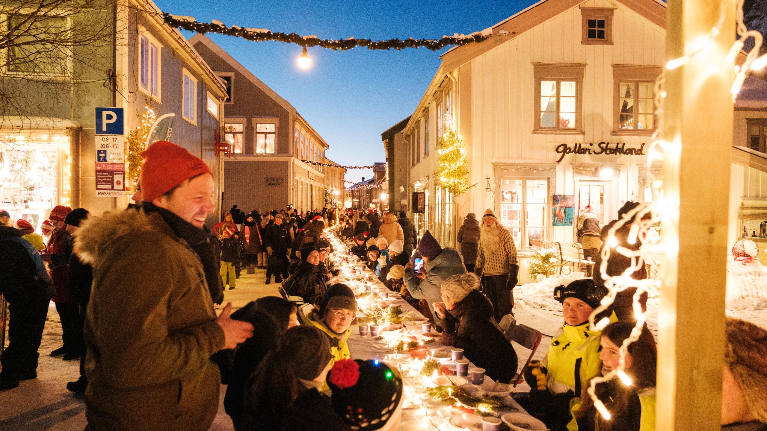 People enjoying porrige with a long table outside.
