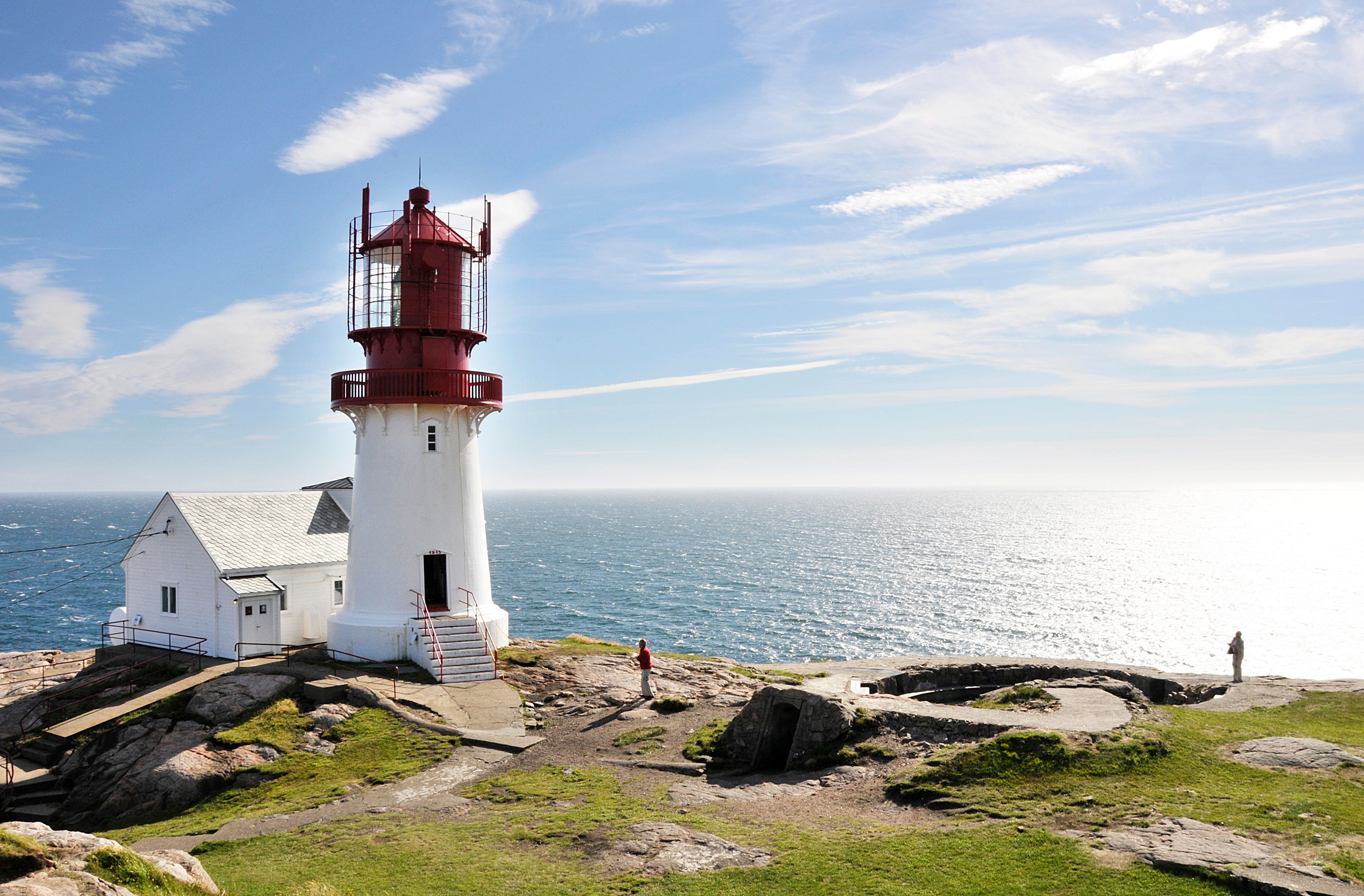 Vista del faro de Lindesnes, pintado en rojo y blanco, en un día soleado frente a la costa, en el Sur de Noruega.