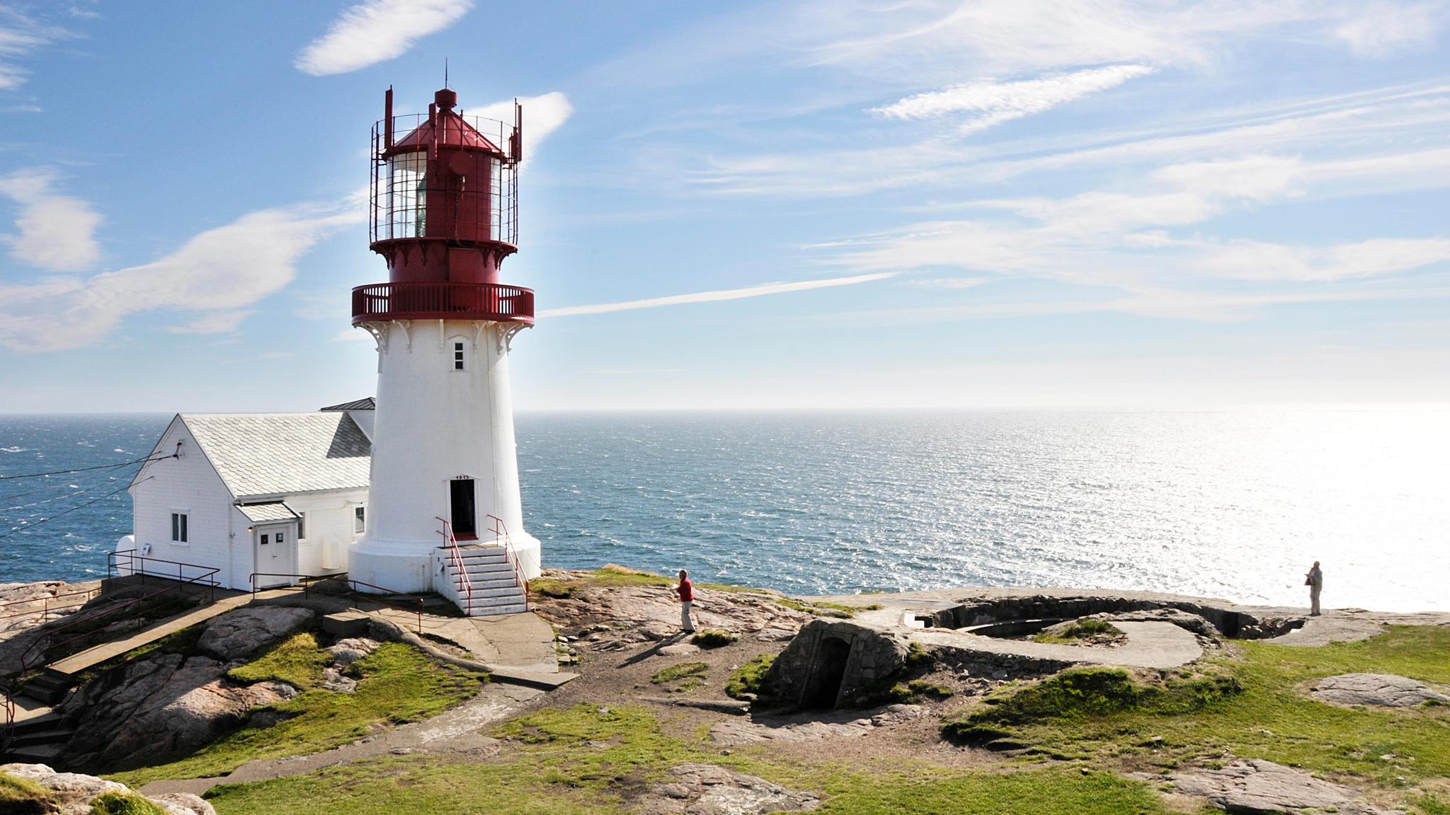 Vista del faro de Lindesnes, pintado en rojo y blanco, en un día soleado frente a la costa, en el Sur de Noruega.