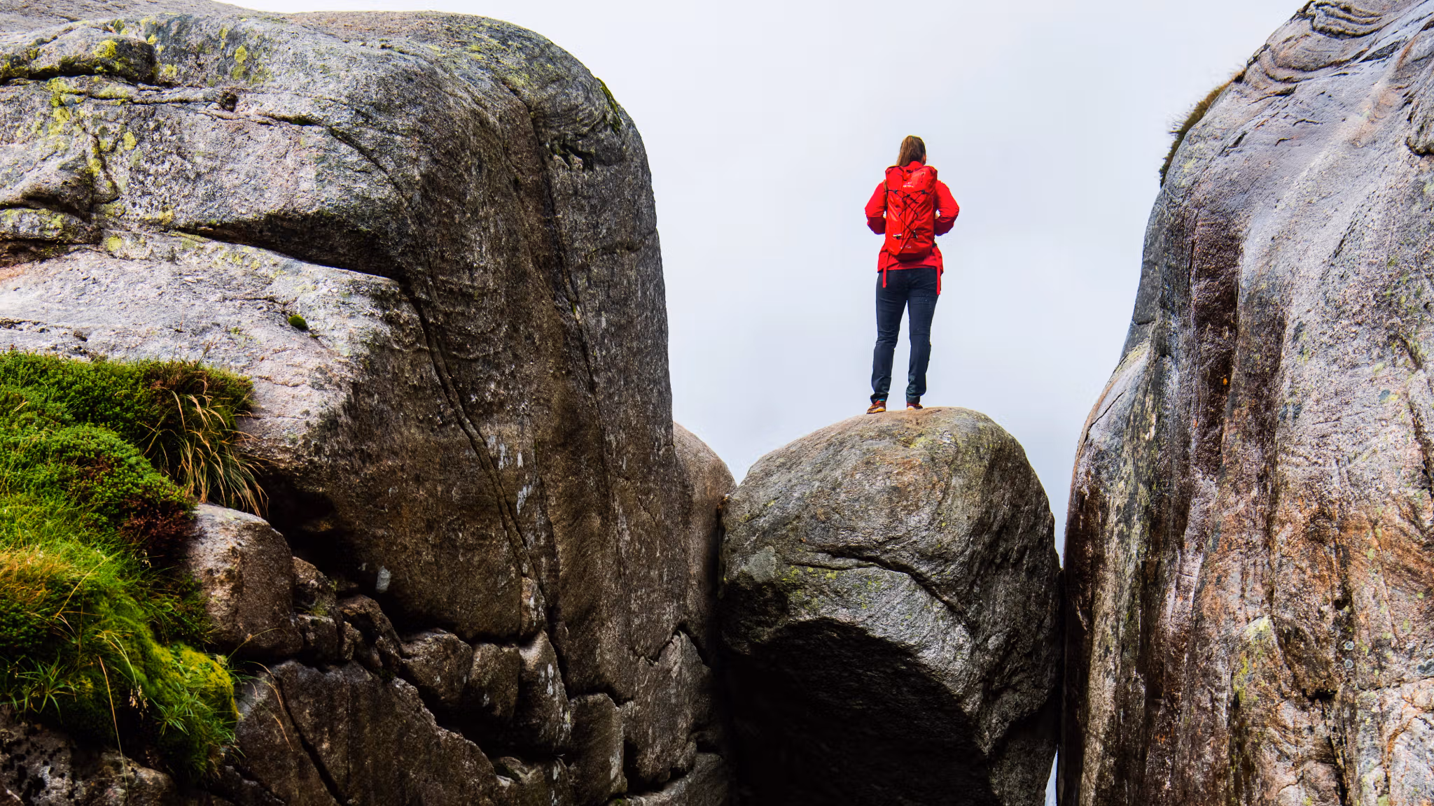 A woman standing on the famous Kjeragbolten rock on Mount Kjerag in Ryfylke, Fjord Norway