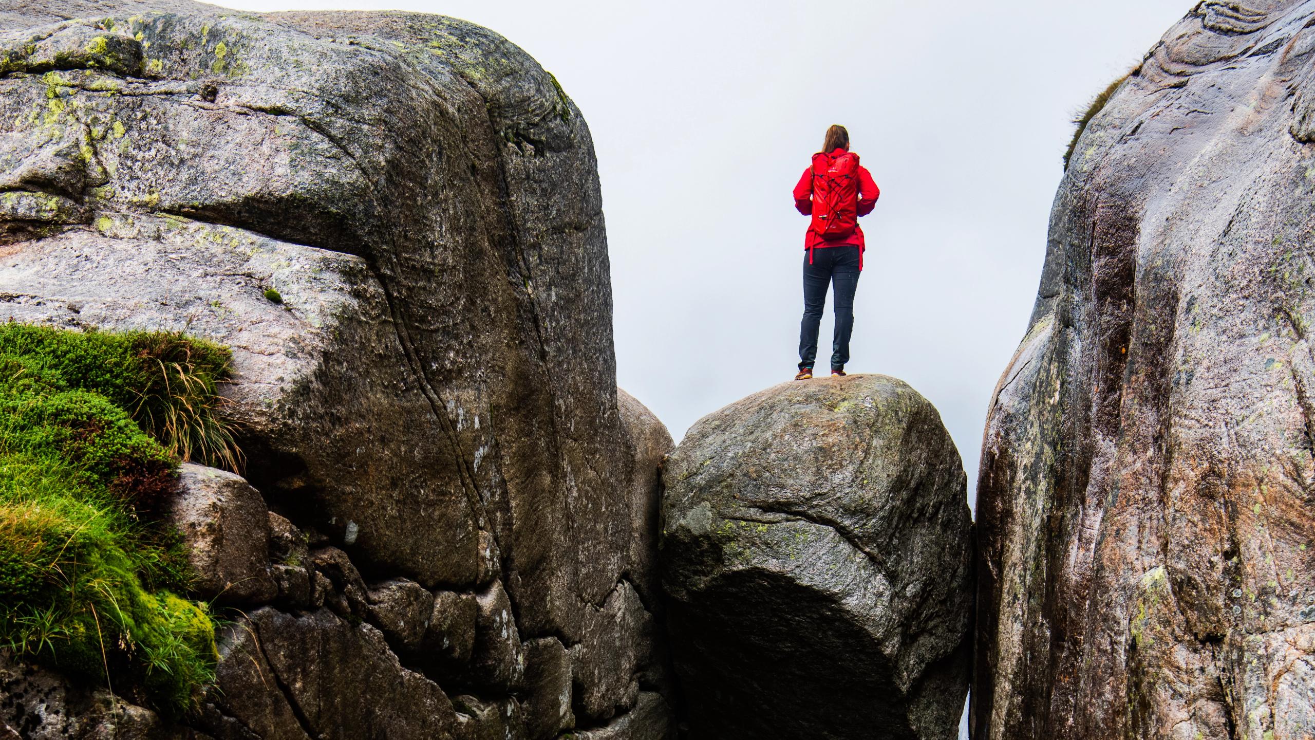 A woman standing on the famous Kjeragbolten rock on Mount Kjerag in Ryfylke, Fjord Norway