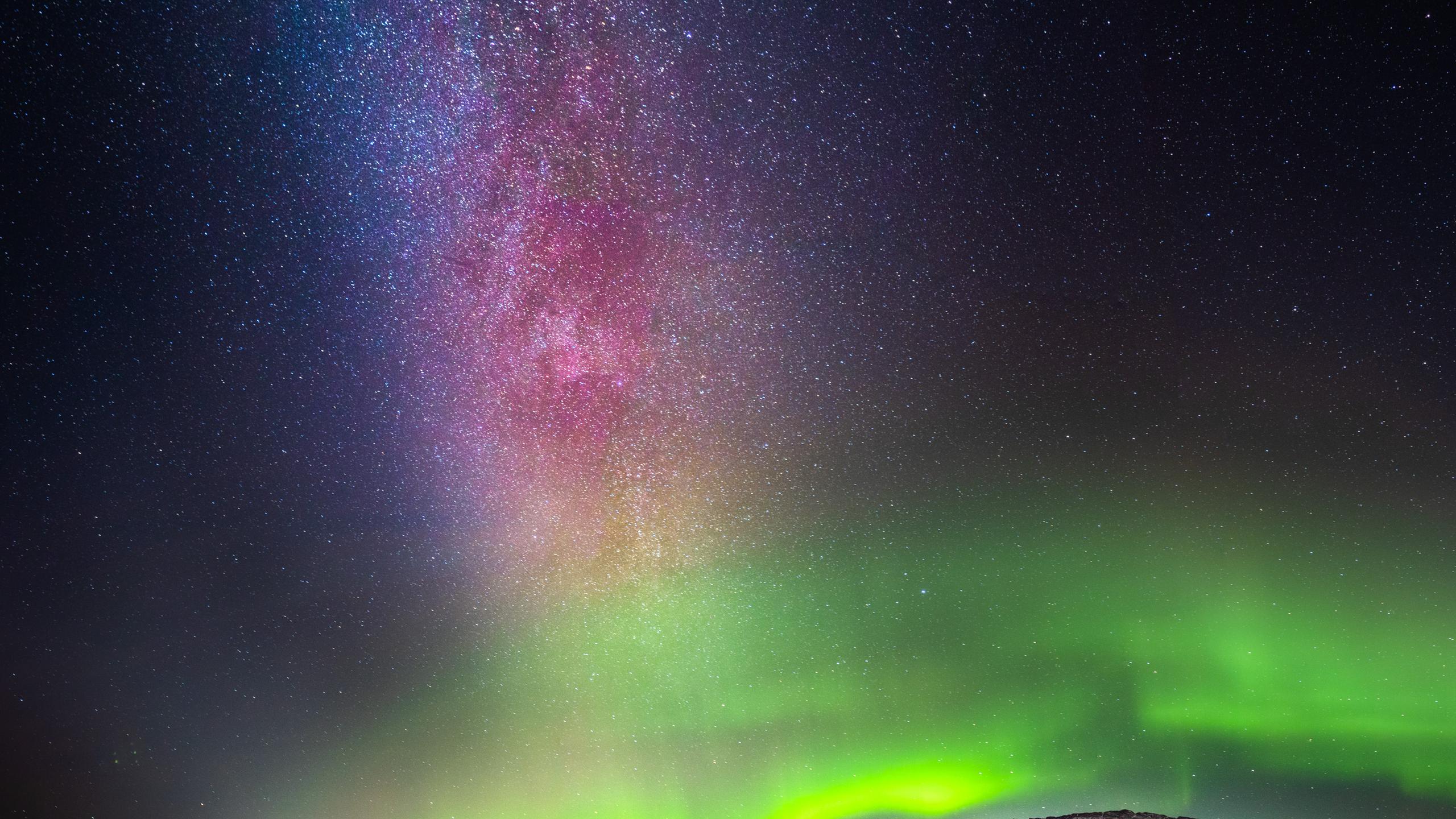 Northern lights and a starry sky over mountains.