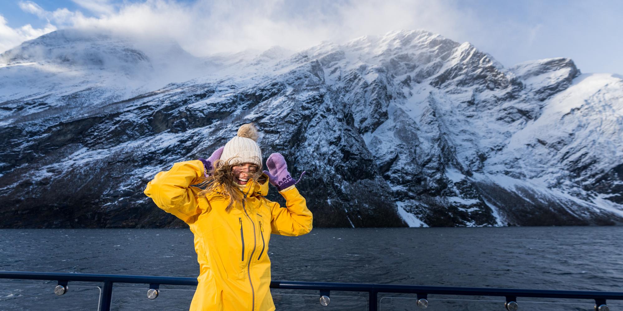 Kvinne på taket av sightseeingbåten fra Ålesund til Geirangerfjorden om vinteren