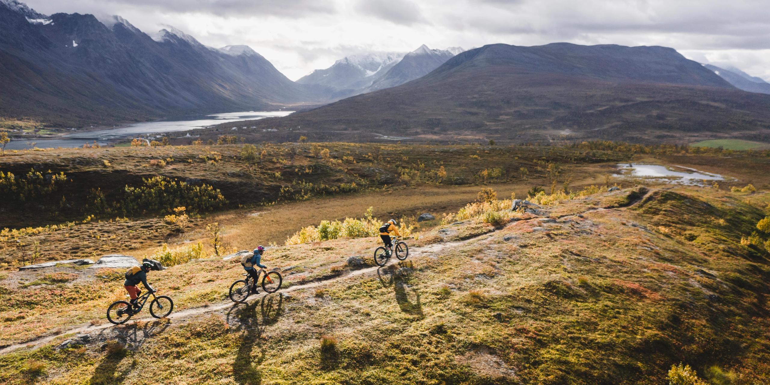 Three people mountain biking in the Lyngenfjord region in Northern Norway, in the mountains