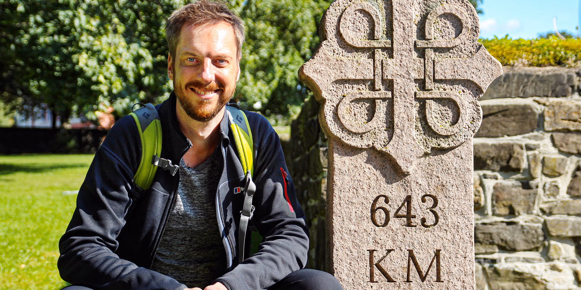 Pilgrim Kes Blans next to a sign that marks the start of the St. Olav Ways pilgrim path from Oslo to Trondheim, Norway