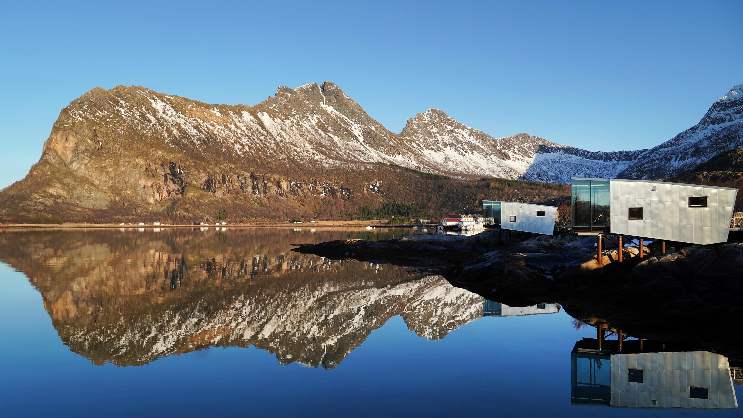 Hytter ved havet med fjell i bakgrunnen.
