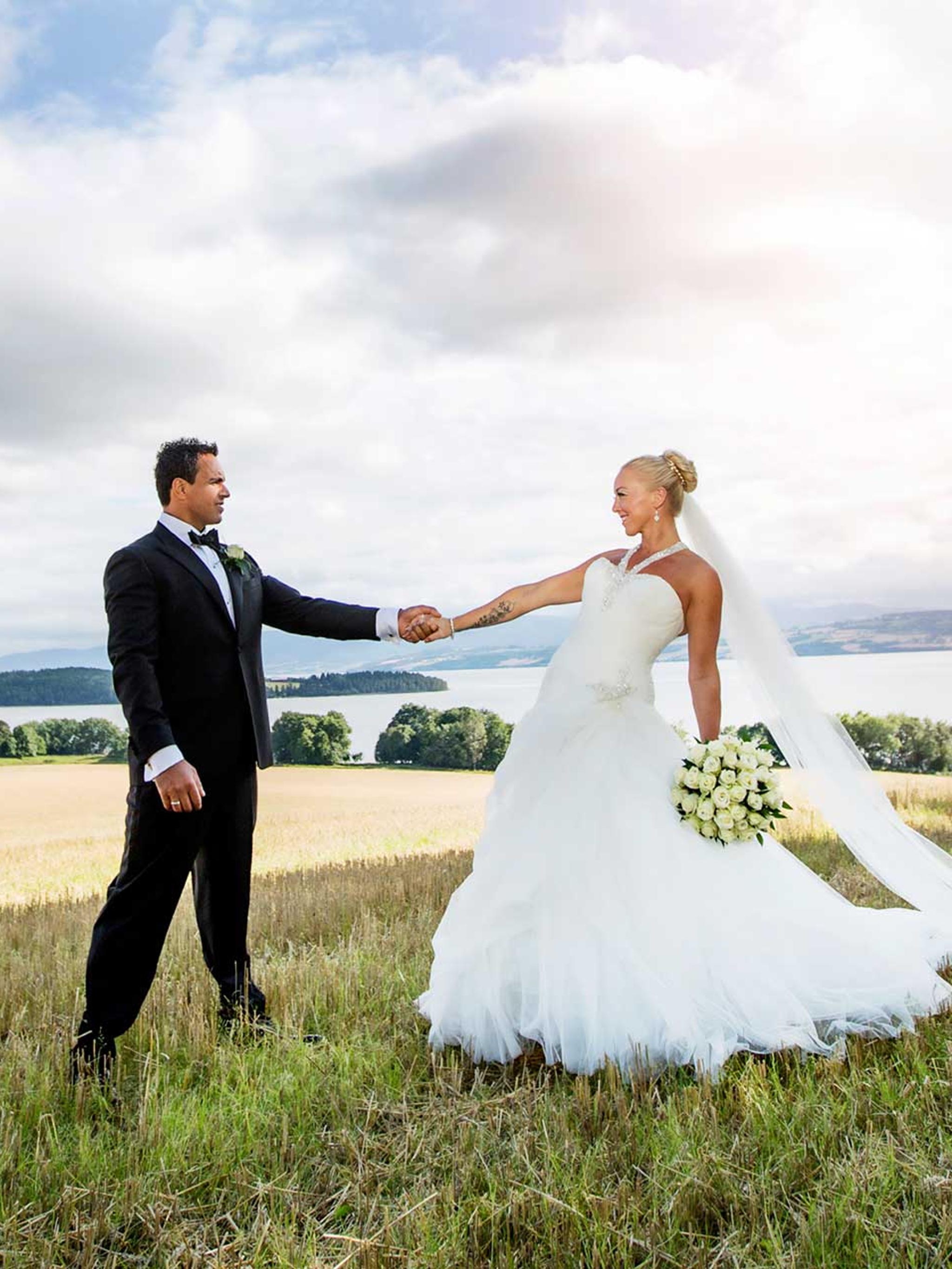A wedding couple holding hands at the fields by Hoel farm in Eastern Norway