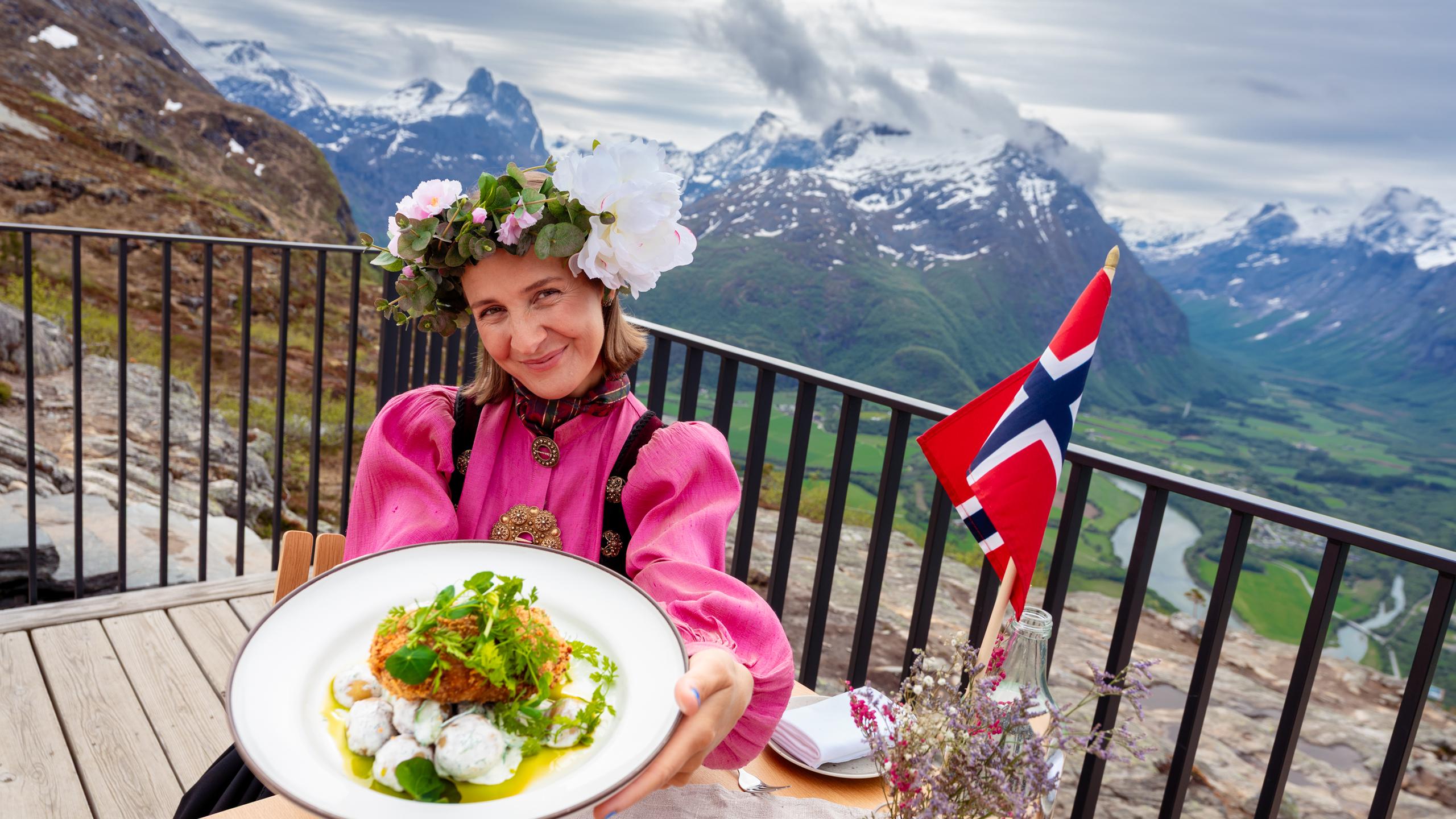 A woman holding a plate of food on a restaurant with a view.