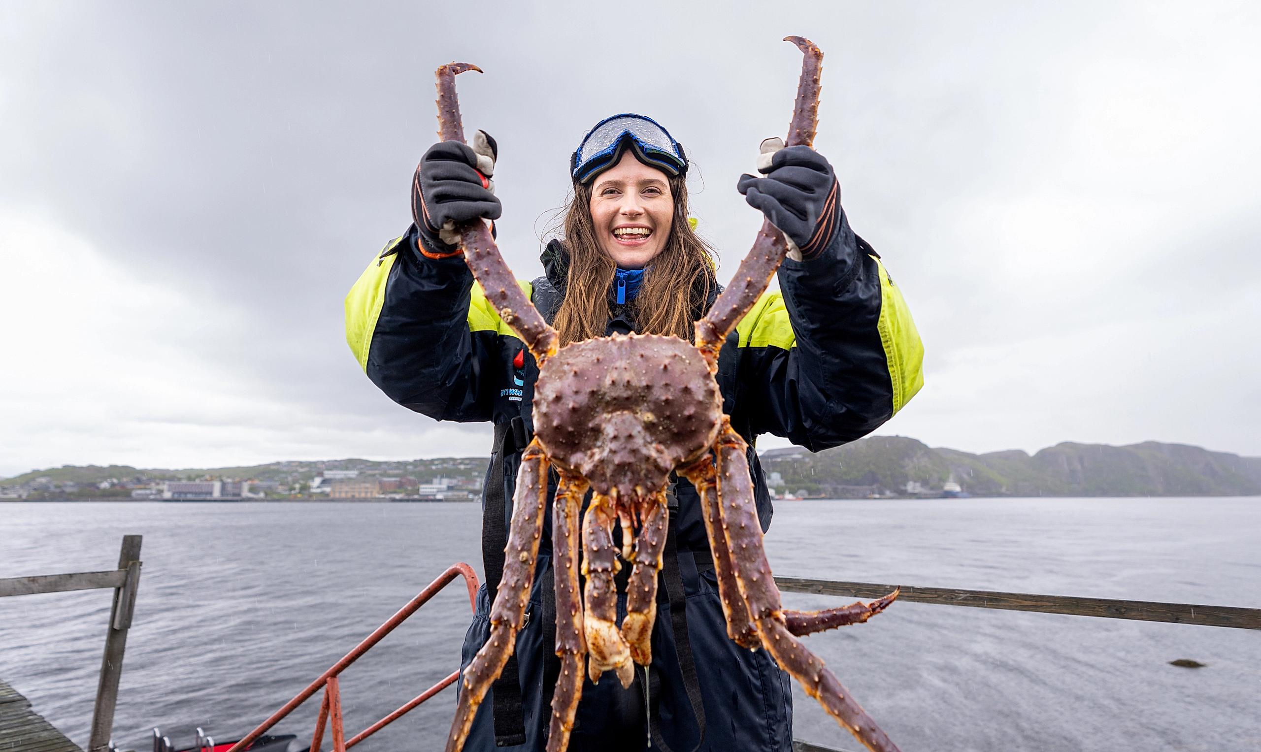 A woman holding a king crab on a king crab safari outside of Kirkenes, Northern Norway
